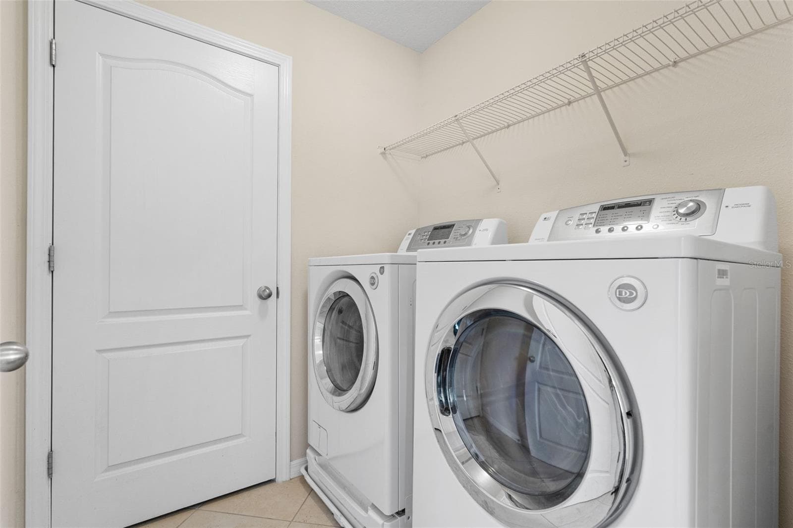 Laundry Room – Dedicated interior laundry room with washer and dryer, overhead shelving, and tile flooring. - 13728 REINDEER CIR, HUDSON