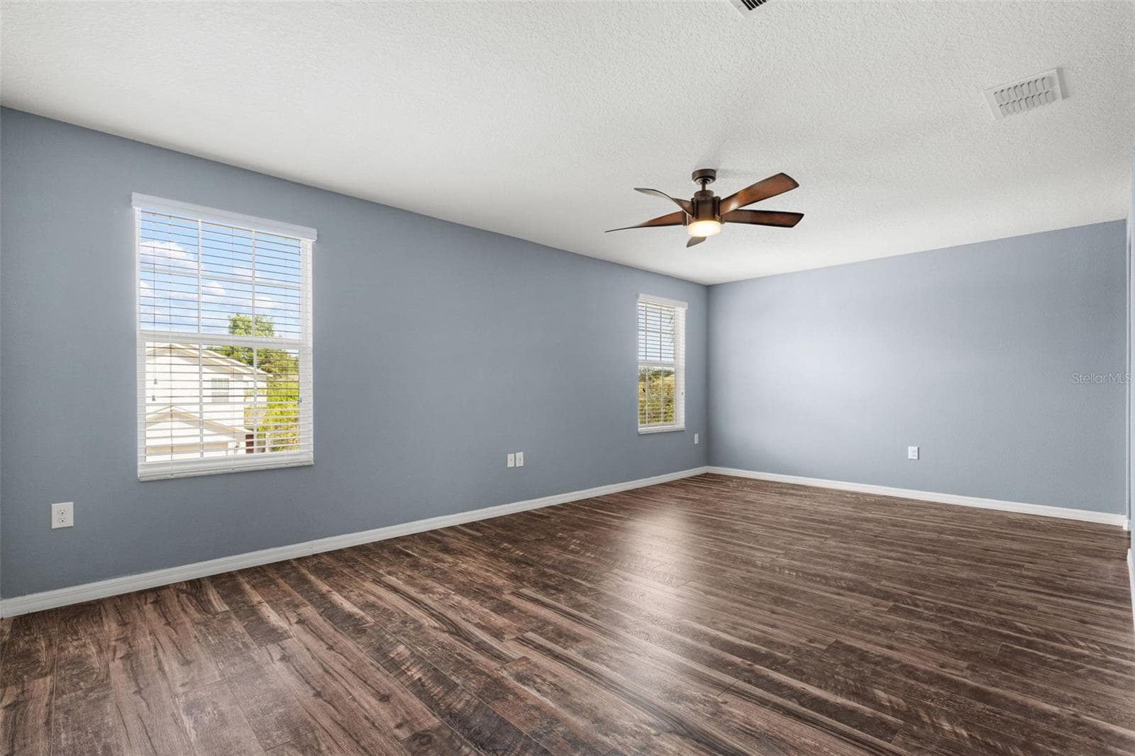 Primary Bedroom – Spacious primary bedroom featuring wood-look flooring, ceiling fan, multiple windows, and abundant natural light. - 13728 REINDEER CIR, HUDSON