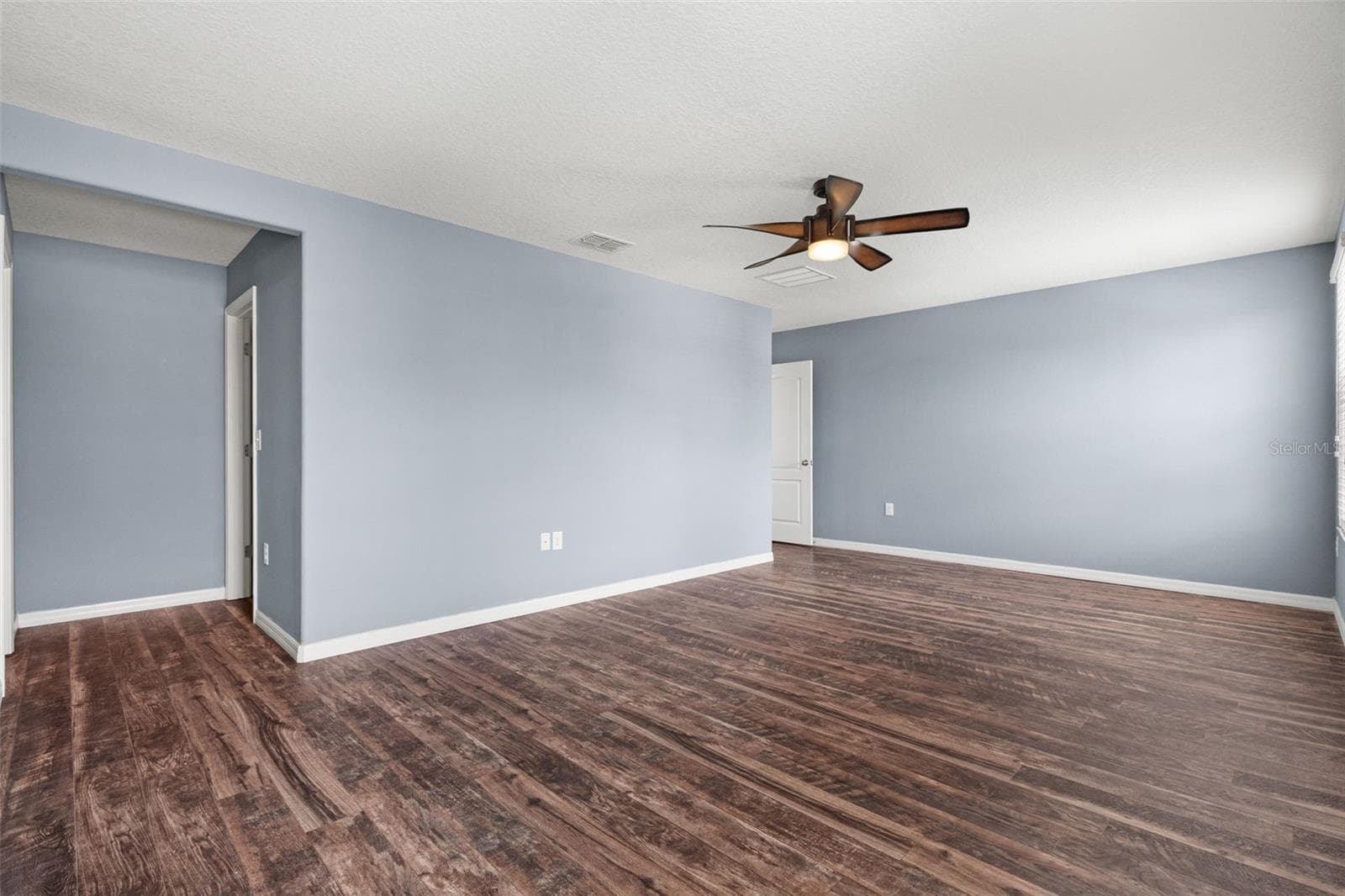 Primary Bedroom – Additional view of the generously sized primary bedroom with wood-look flooring and ceiling fan. - 13728 REINDEER CIR, HUDSON