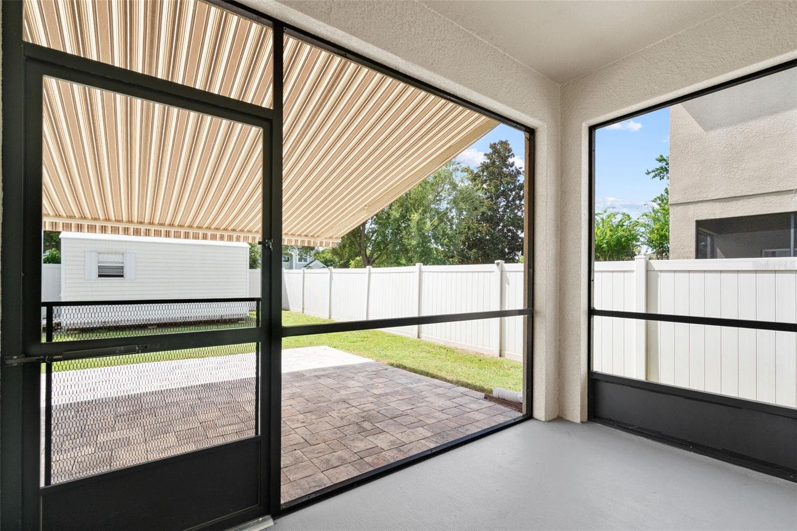 Screened Patio – Covered and screened rear patio overlooking the fenced backyard, offering a comfortable outdoor living space. - 13728 REINDEER CIR, HUDSON