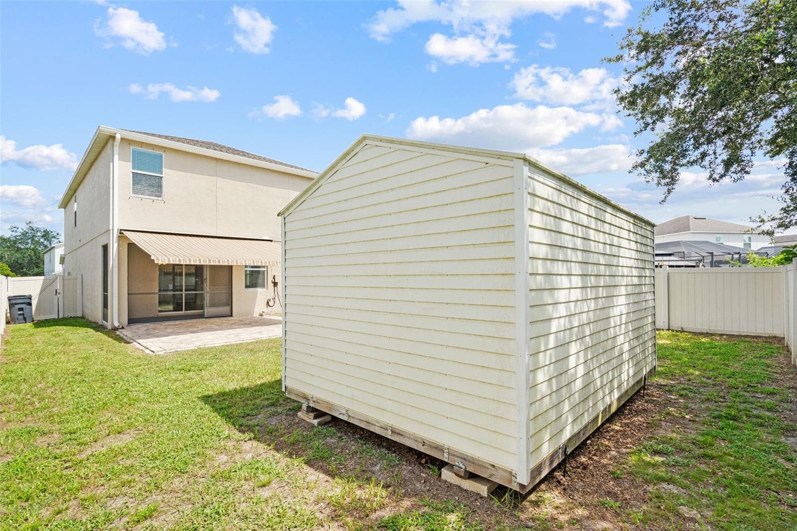 Backyard & Storage Shed – Spacious fenced backyard featuring a large detached storage shed and rear patio area. - 13728 REINDEER CIR, HUDSON