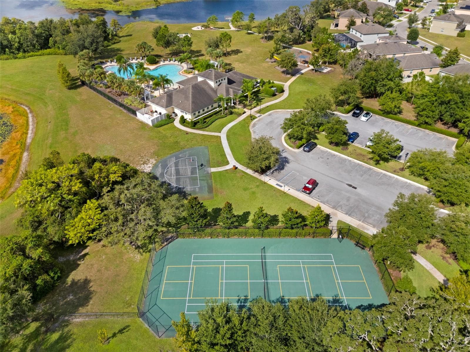 Community Recreation Area – Aerial view showcasing the community tennis courts, basketball court, clubhouse, pool, and nearby parking. - 13728 REINDEER CIR, HUDSON