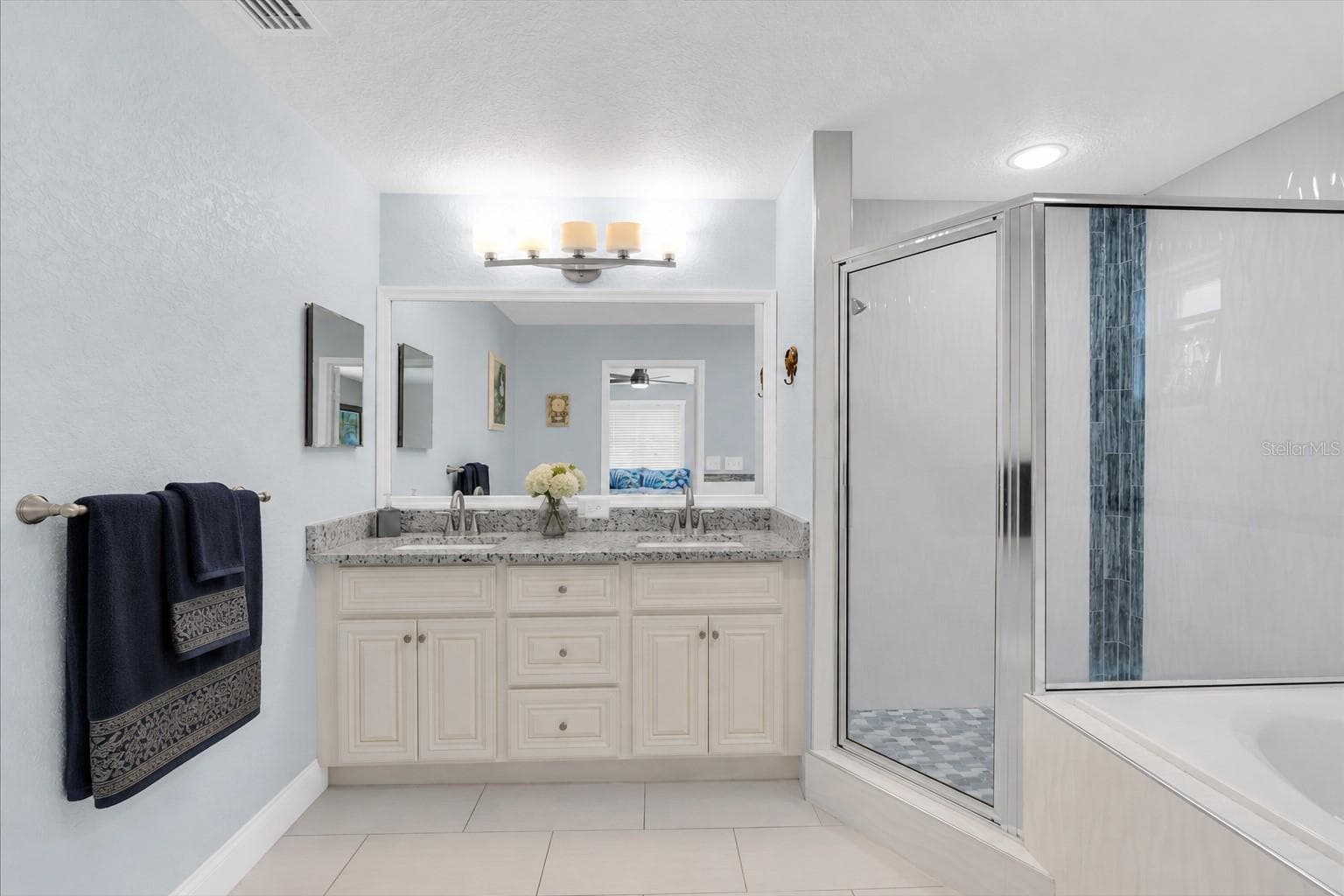 The primary bathroom is spacious with double sinks, a glass shower enclosure and a jetted, deep tub. - 6501 MOCKINGBIRD WAY S, GULFPORT