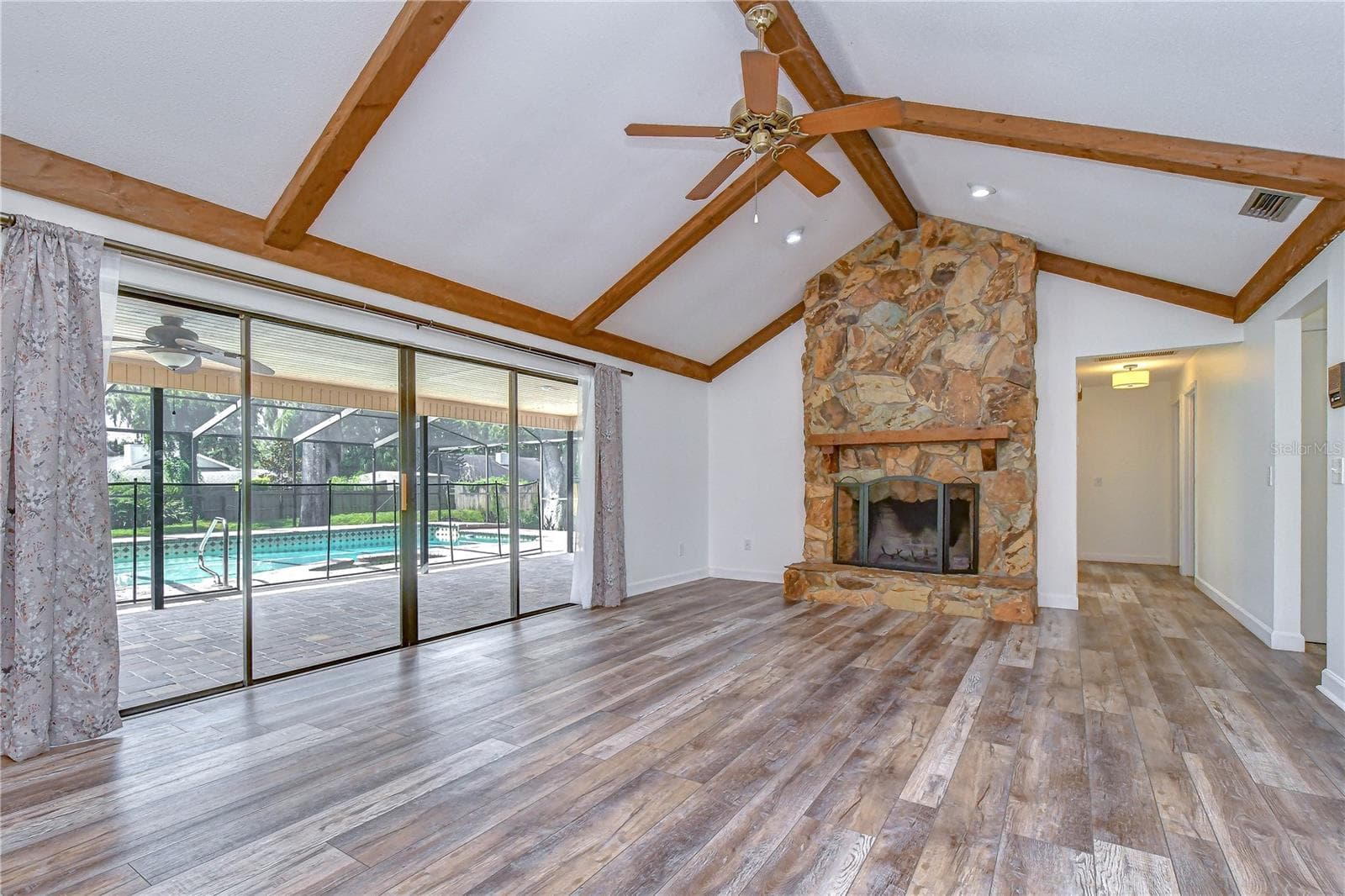 Open gathering space featuring beamed vaulted ceilings and a cozy wood-burning fireplace - 1101 OAKRIDGE MANOR DR, BRANDON