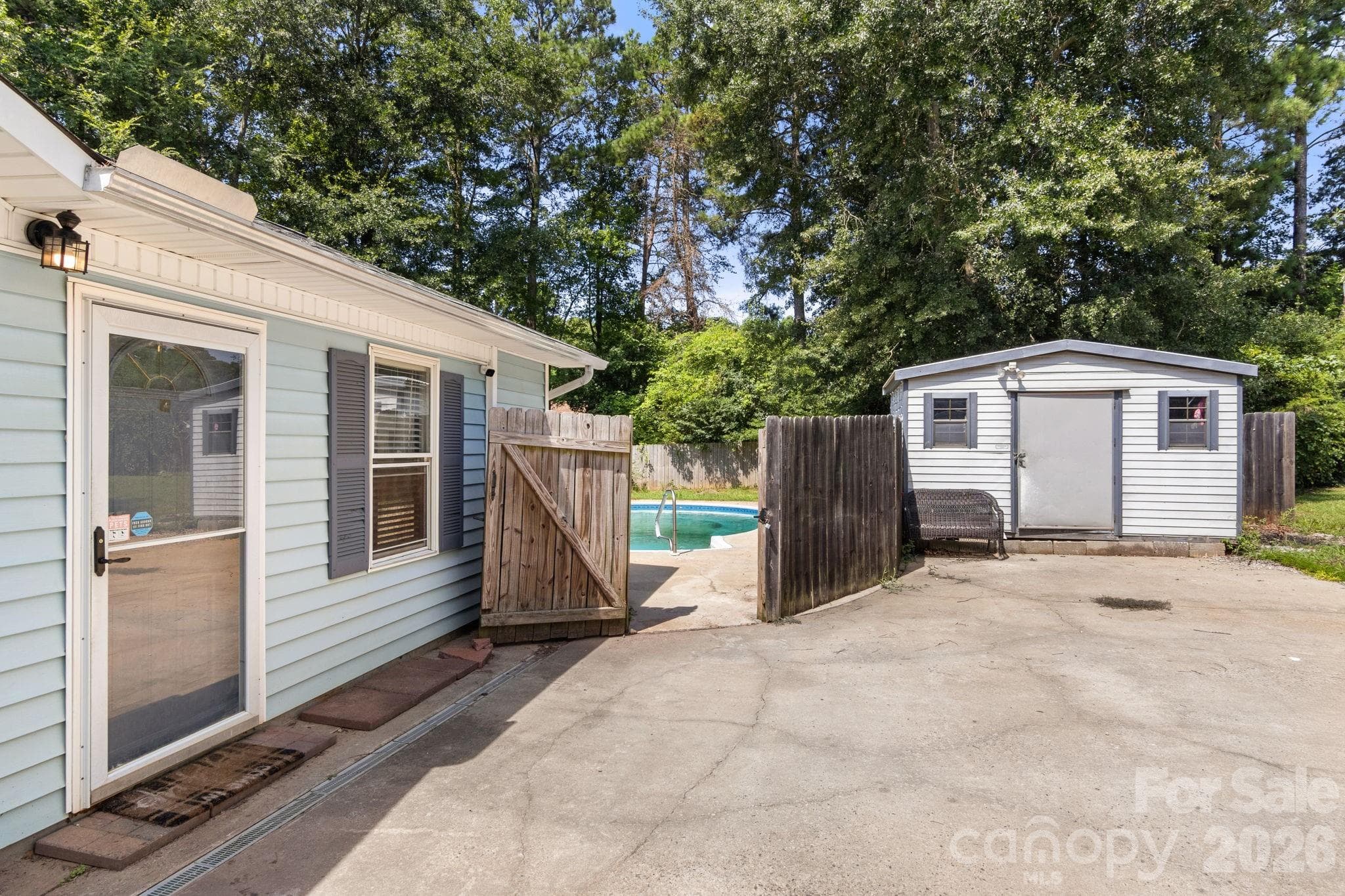 Large shed conveys with the home. Side door into bonus room and view of privacy fence and pool - 1820 Bridgewood Drive, Lancaster