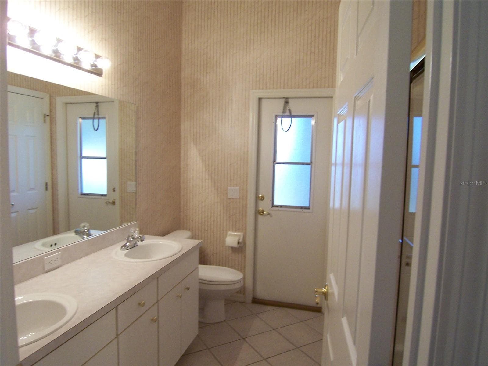 BATH 2 - dual sinks - tub/shower and linen closet - DOOR LEADS OUT TP SCREENED LANAI  Wallpaper being removed - 5435 SUMMERLAND HILLS DR, LAKELAND