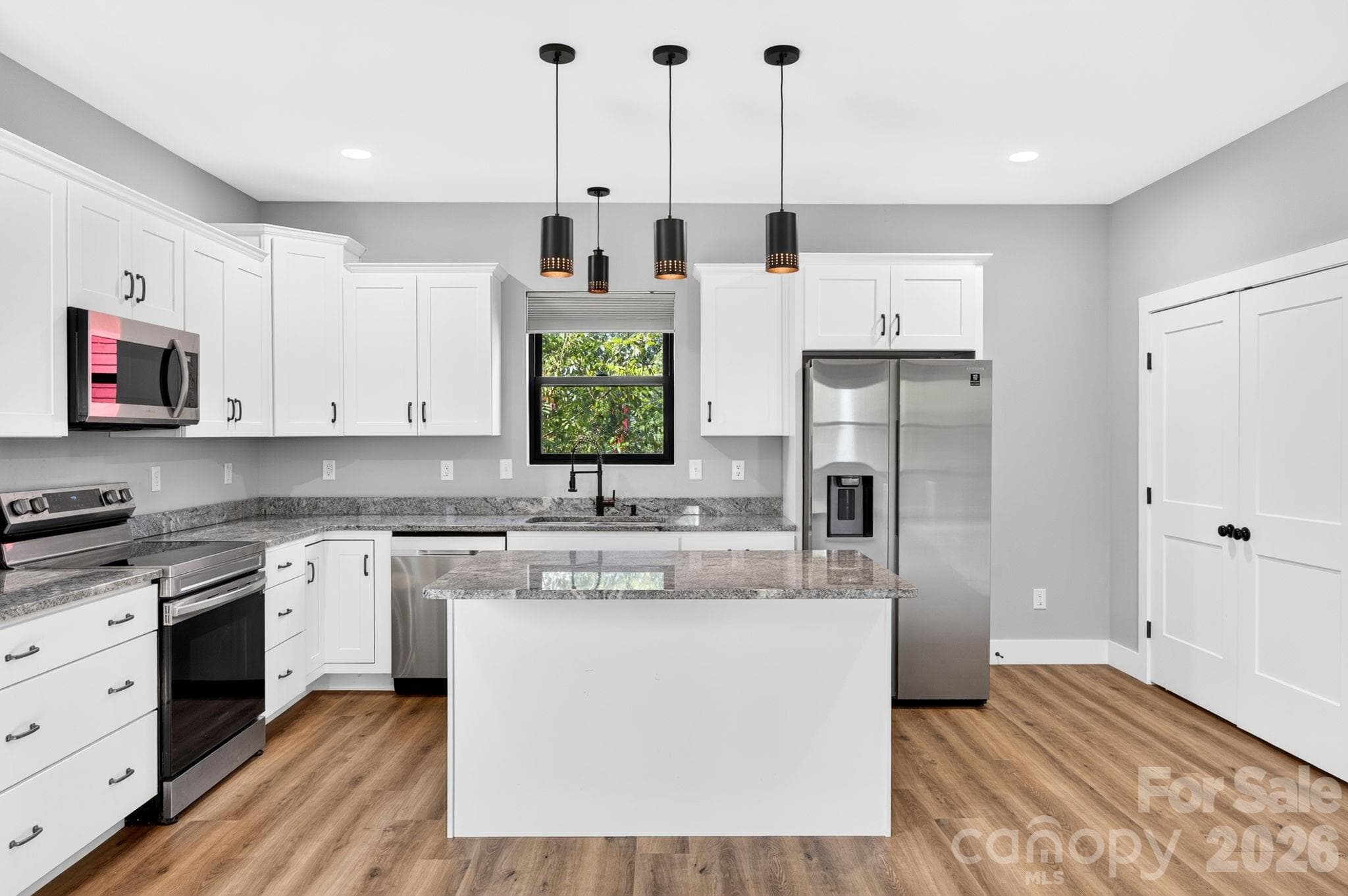 Energy-efficient kitchen featuring high-end stainless steel appliances, sustainable materials, and bright natural lighting designed for green living. - 613 Salem Heights Lane, Swannanoa
