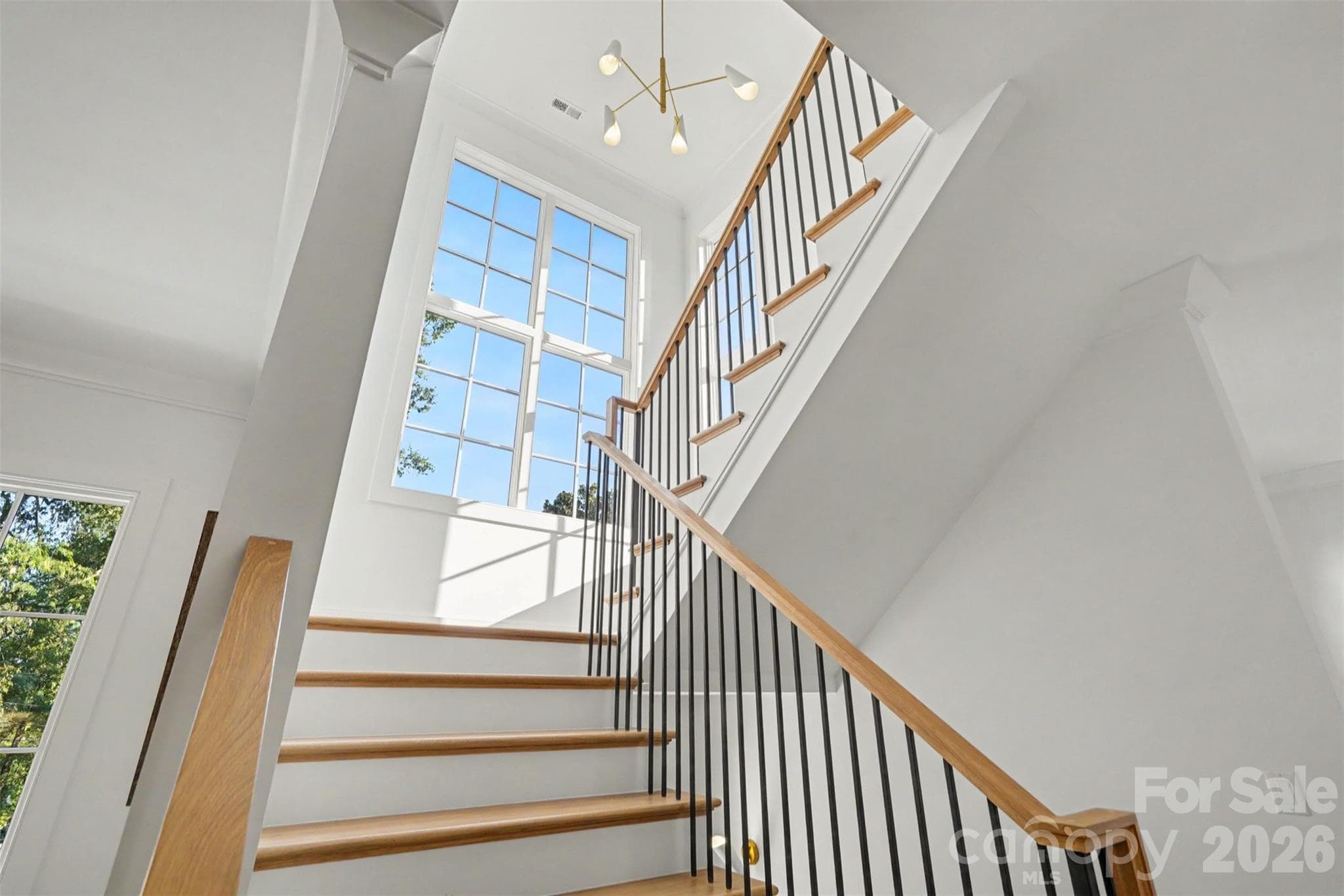 A sun-drenched staircase framed by soaring window - 539 Mammoth Oaks Drive, Charlotte