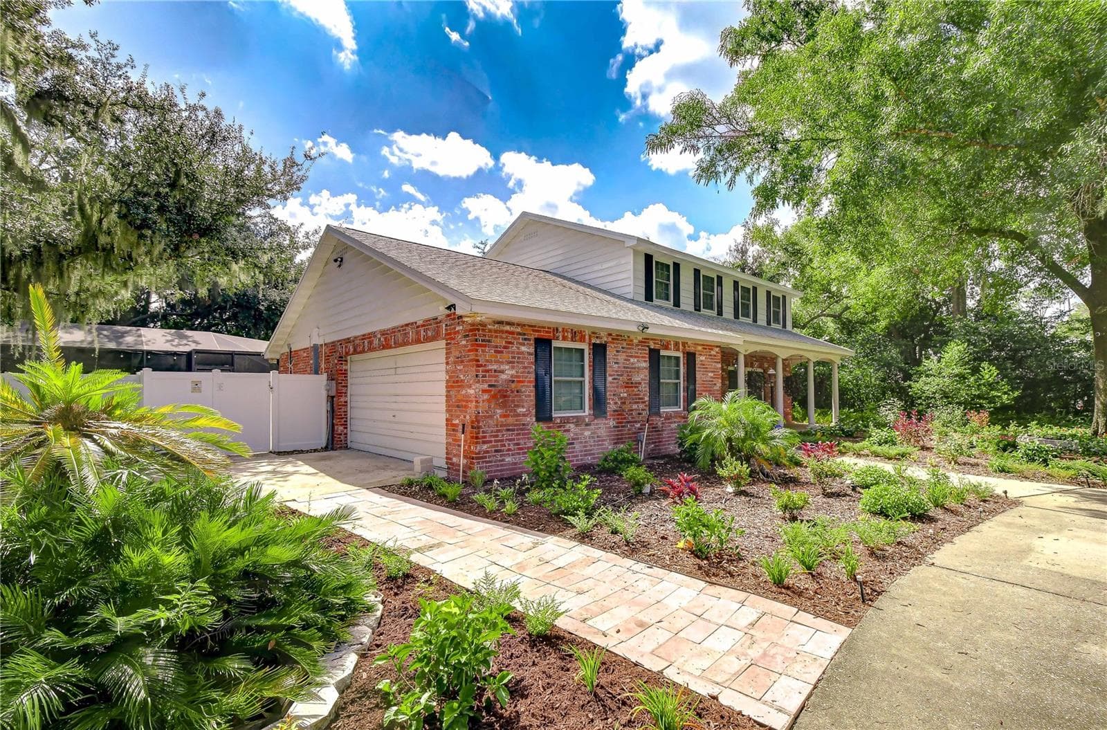 Side view showcasing the classic brick exterior, fresh front landscaping, and wide paved driveway. - 901 WOODVIEW DR, BRANDON