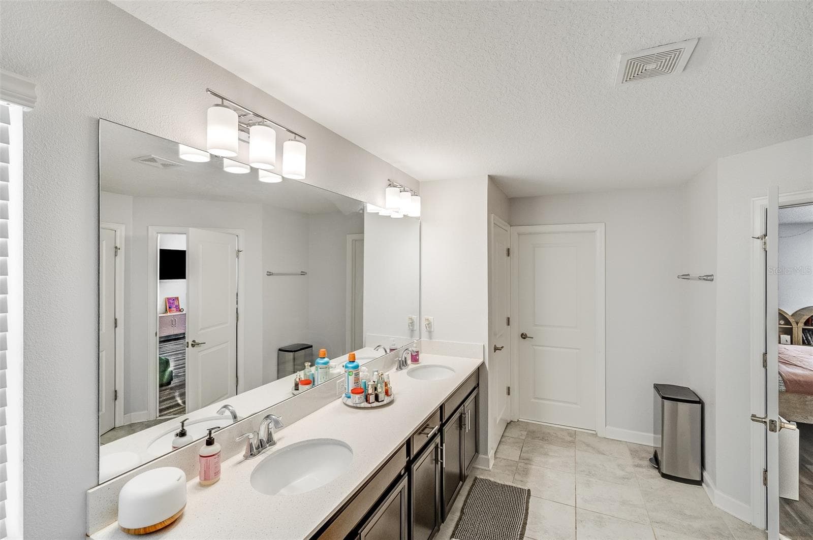 View of dual sinks, linen closet and walk-in closet for the primary suite - 2353 CRESCENT MOON ST, KISSIMMEE