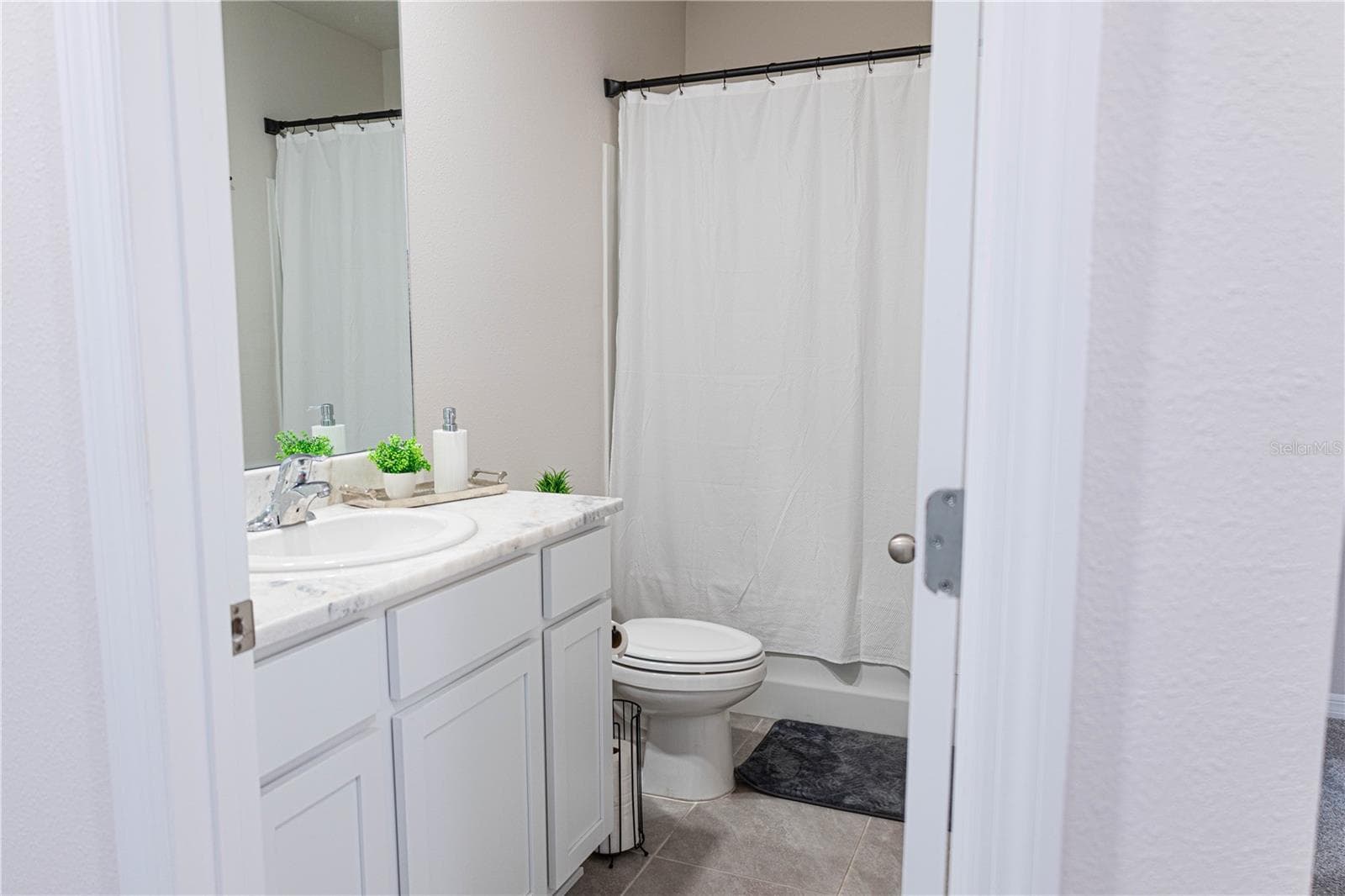 Primary en-suite bath with dual sinks, quartz countertops, and a walk-in shower — a private retreat off the main bedroom - 17632 CRESCENT MOON LOOP, BRADENTON