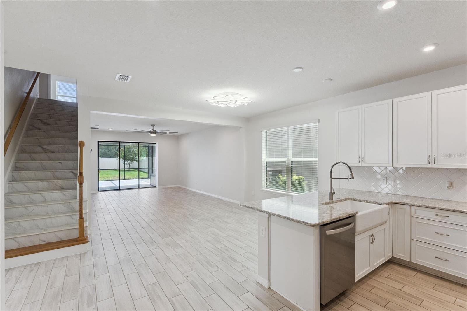 Kitchen & Main Living Area – Wide view highlights the home's open layout, with the kitchen flowing into the spacious living area and sliding glass doors extending the sightline to the screened patio and backyard. - 1287 VERDANT GLADE PL, WINTER PARK