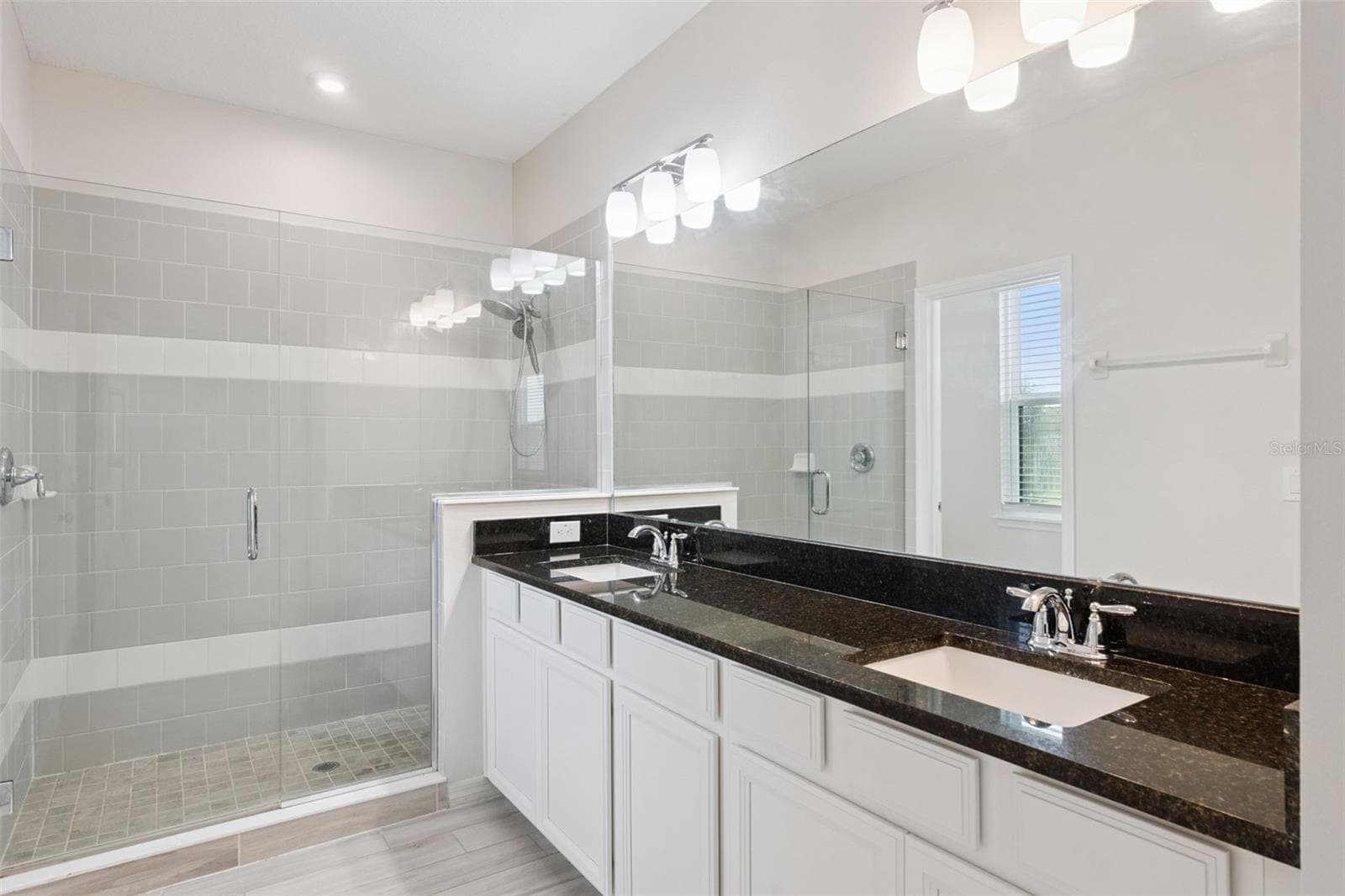 2nd Primary Bathroom – Primary bath showcases a large glass-enclosed tiled shower alongside the dual-sink vanity, creating a bright and functional ensuite retreat. - 1287 VERDANT GLADE PL, WINTER PARK