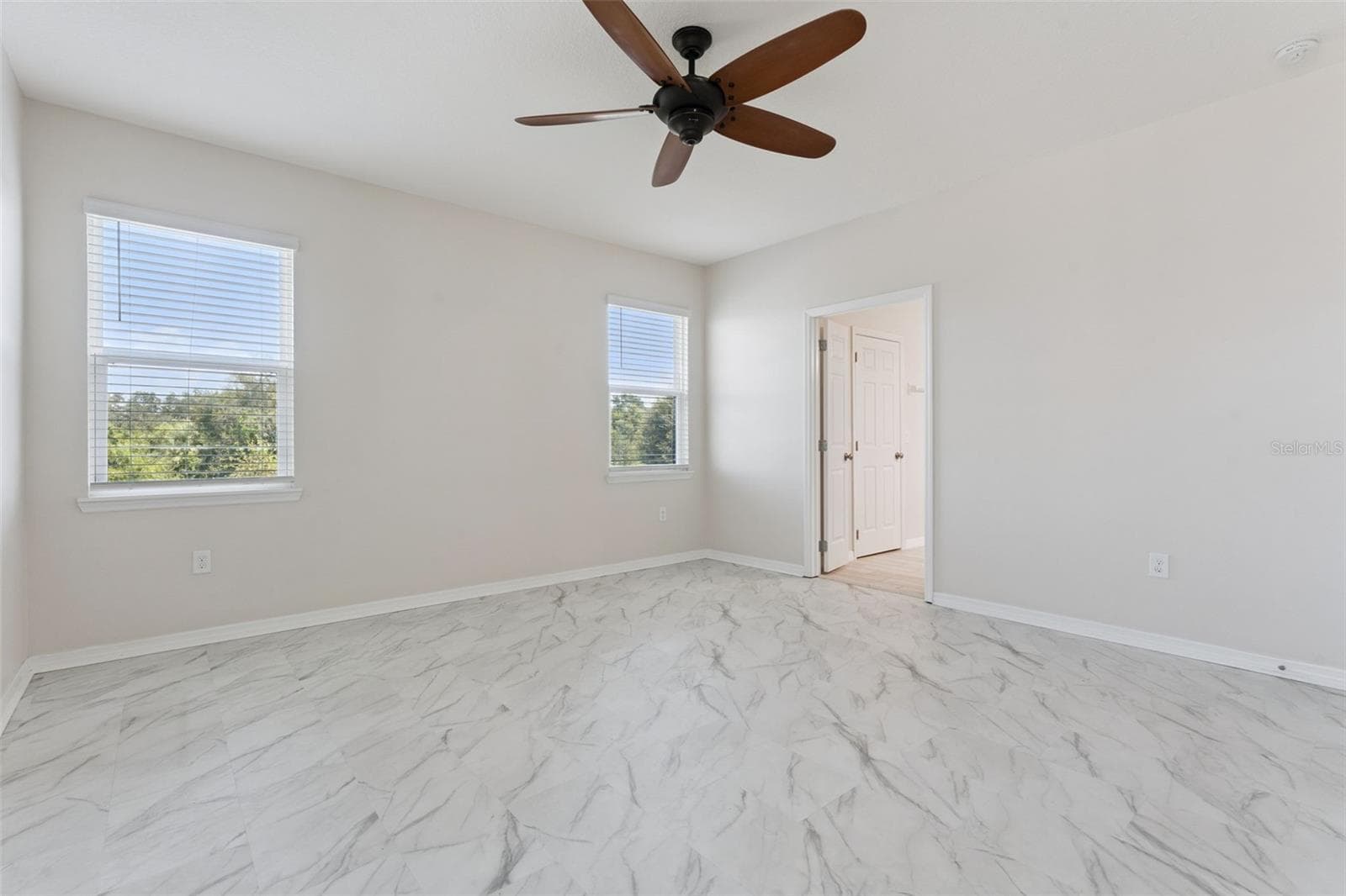 2nd Primary Suite (Upstairs) – Alternate view highlights the generous room dimensions, bright neutral finishes, and multiple windows overlooking the surrounding greenery. - 1287 VERDANT GLADE PL, WINTER PARK