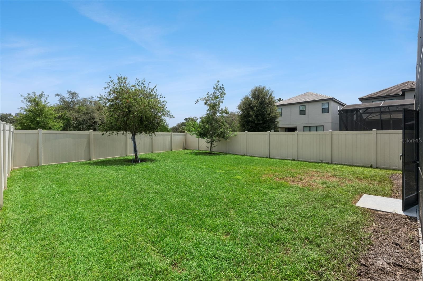 Fenced Backyard – Wide backyard view highlights the open lawn, established trees, and privacy fencing around the property. - 1287 VERDANT GLADE PL, WINTER PARK
