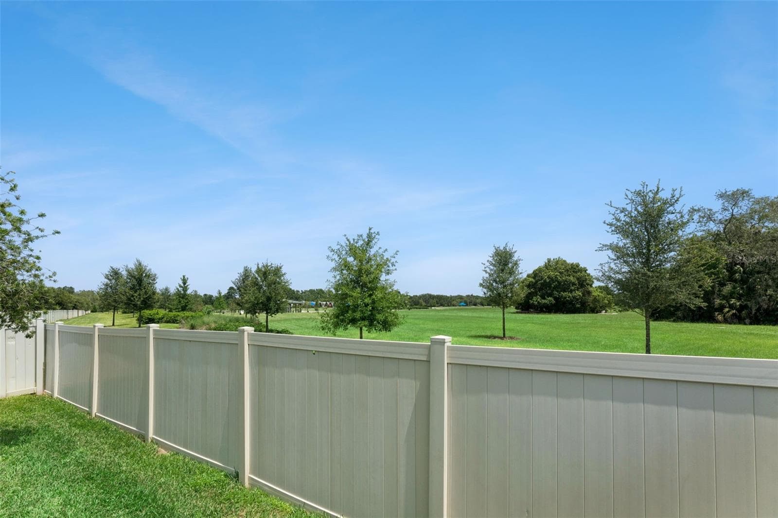 Fenced Backyard – The backyard enjoys an open outlook beyond the rear fence, with expansive maintained green space and mature trees in view. - 1287 VERDANT GLADE PL, WINTER PARK