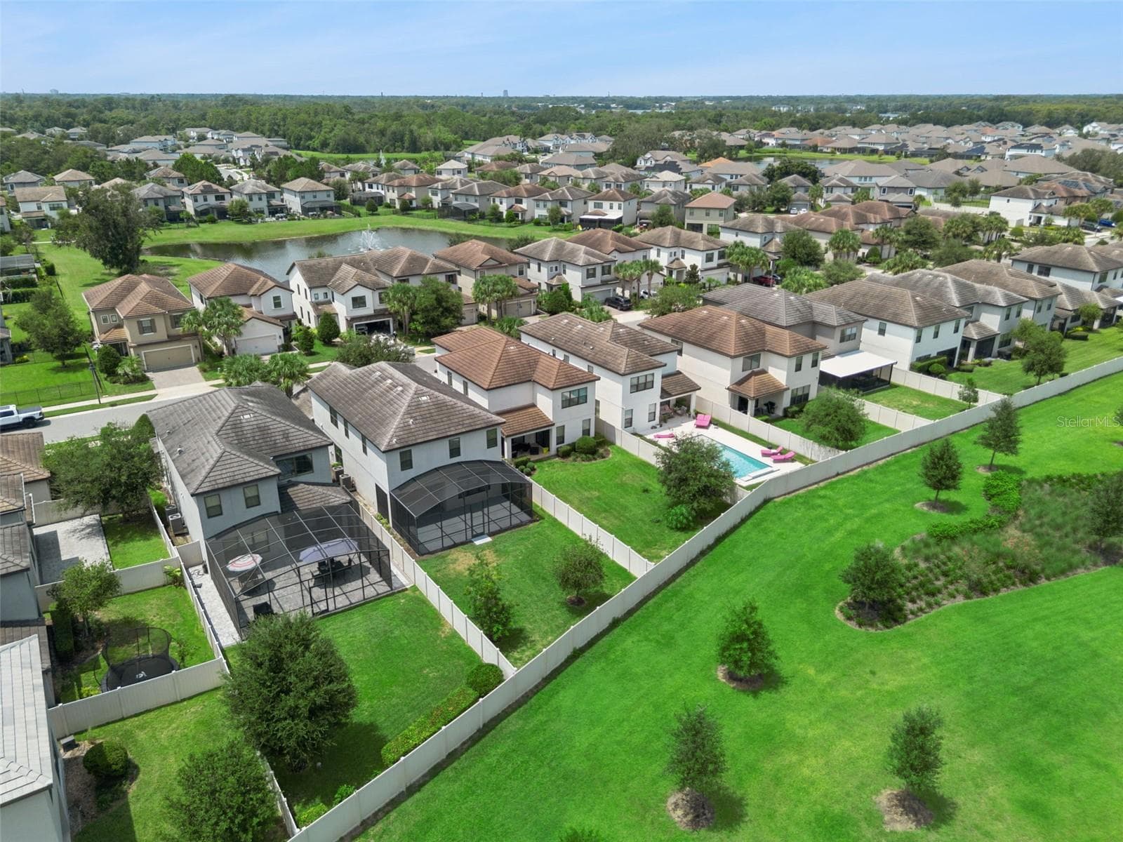 Aerial view captures the surrounding residential setting, nearby pond, and extensive landscaped green areas throughout the community. - 1287 VERDANT GLADE PL, WINTER PARK