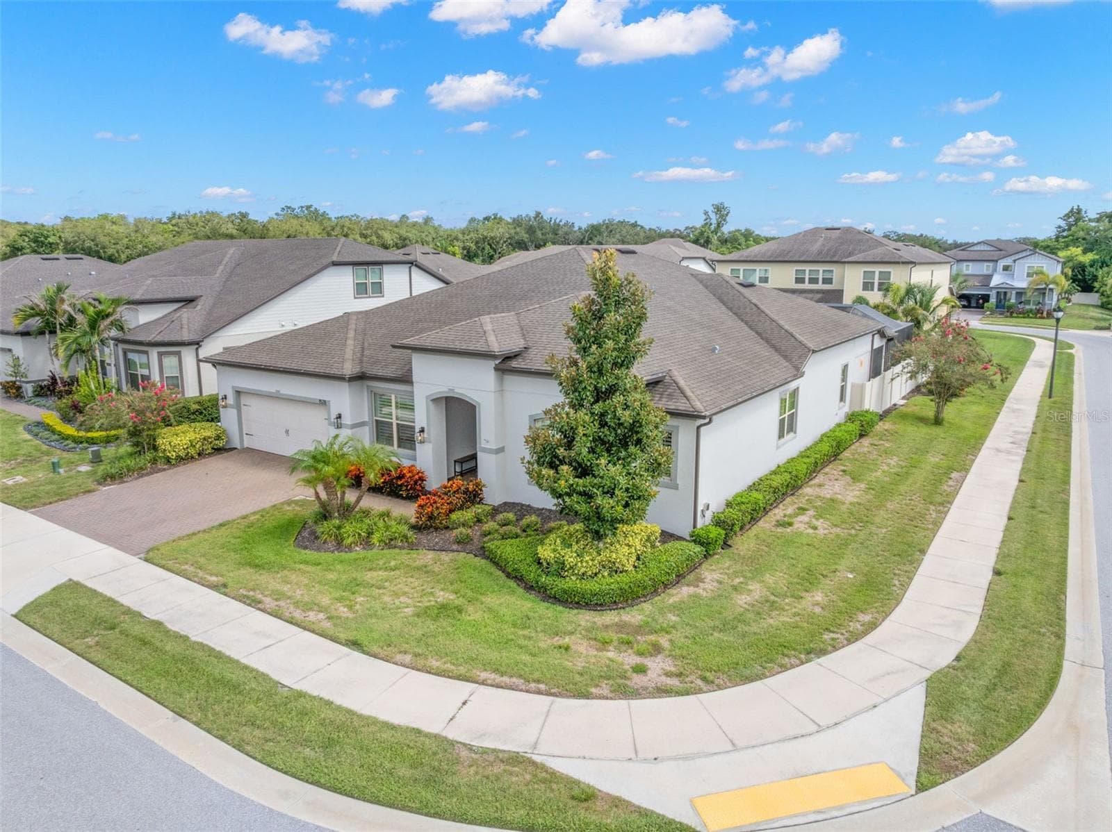 An elevated view highlights the home’s substantial single-story footprint, manicured landscaping and generous corner-lot setting within the gated Enclave at Palm Harbor. - 1528 FOREST GLEN CT, PALM HARBOR