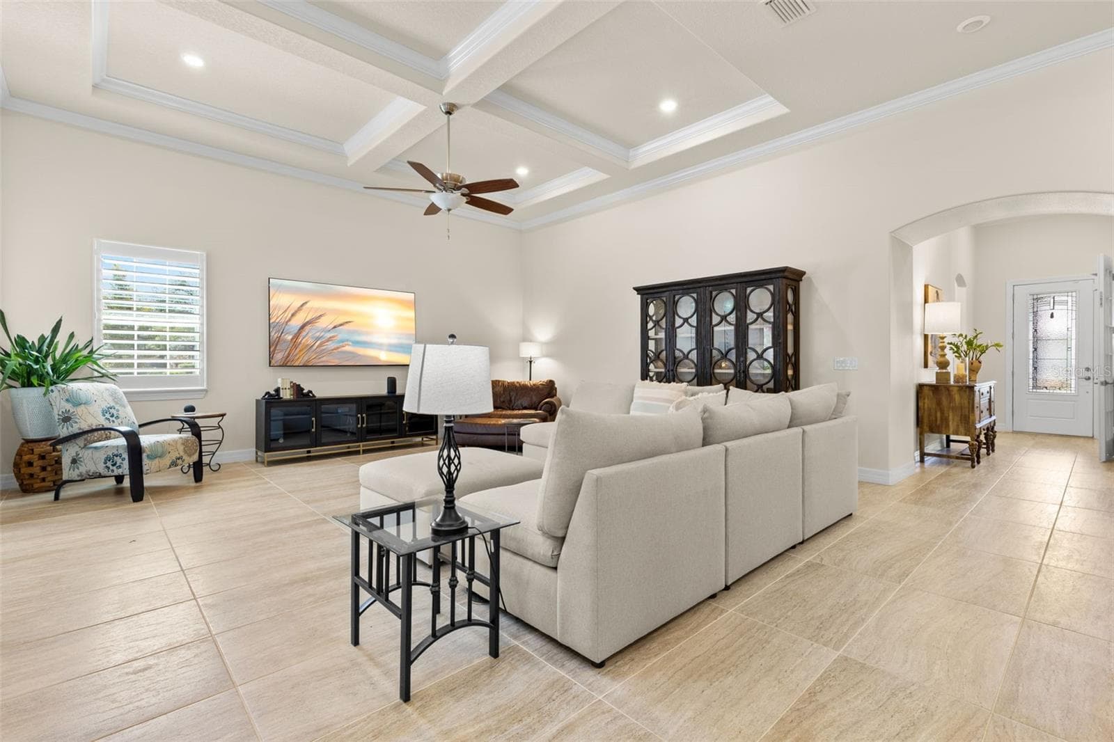 The main living area makes an immediate impression with 12-foot ceilings, layered tray detailing, crown molding, recessed lighting and oversized tile flooring, while plantation shutters and an open, generously proportioned layout add to the room’s polished feel. - 1528 FOREST GLEN CT, PALM HARBOR