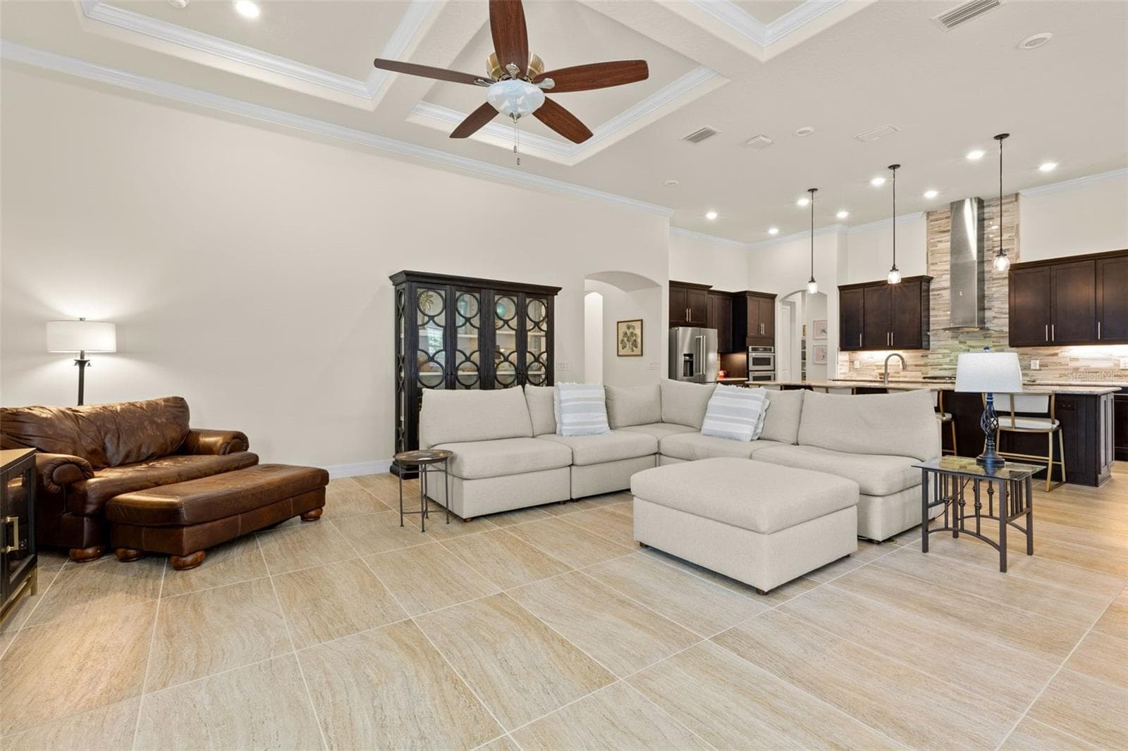 The spacious great room is made for gathering, with soaring tray ceilings, crown molding, oversized tile and plenty of room to create multiple conversation areas, while the open kitchen remains effortlessly connected to the heart of the home. - 1528 FOREST GLEN CT, PALM HARBOR