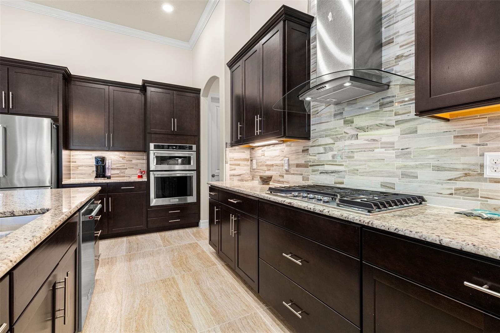 The oversized island earns its place at the center of the home, combining generous prep space, a double sink, dishwasher, deep drawers, additional cabinetry, and casual seating. From here, the kitchen opens effortlessly to both the dining area and great room, creating one expansive space for cooking, gathering, and entertaining. - 1528 FOREST GLEN CT, PALM HARBOR
