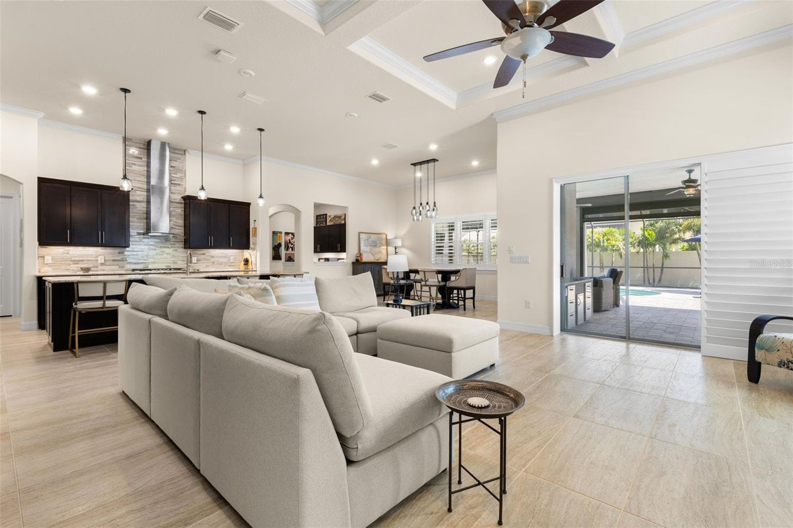 Designed for easy indoor-outdoor living, the open great room flows into the kitchen and dining area, while wide sliding glass doors with plantation shutters open directly to the screened lanai and pool beyond. - 1528 FOREST GLEN CT, PALM HARBOR