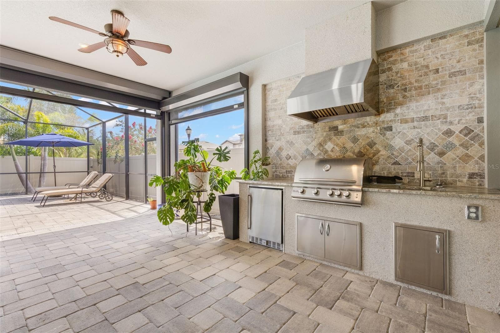 The screened lanai becomes a true outdoor living space with a built-in gas grill, stainless vent hood, utility sink, mini refrigerator, storage and brick-paver flooring — all just steps from the pool and ready for everything from weeknight dinners to weekend entertaining. - 1528 FOREST GLEN CT, PALM HARBOR