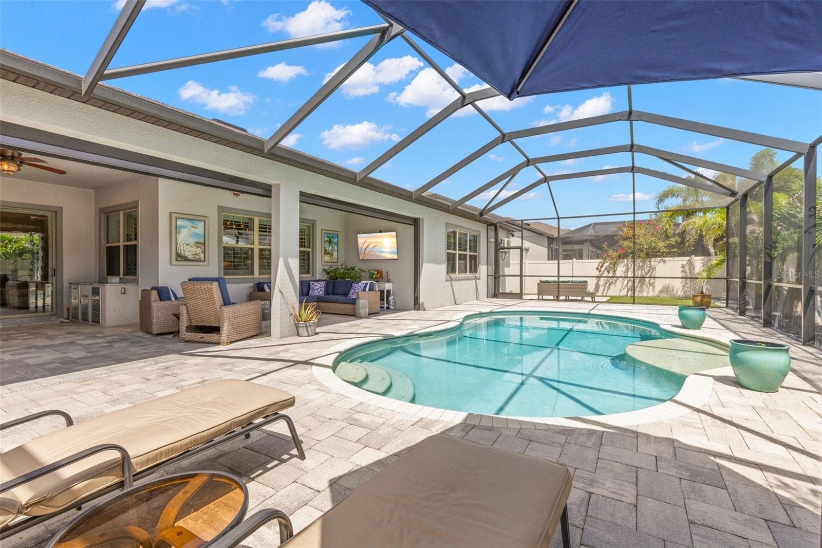 The screened pool area gives outdoor living plenty of room to spread out, with a curving in-ground pool, broad brick-paver deck and both covered and open-air spaces for lounging, dining and enjoying the Florida sunshine. - 1528 FOREST GLEN CT, PALM HARBOR