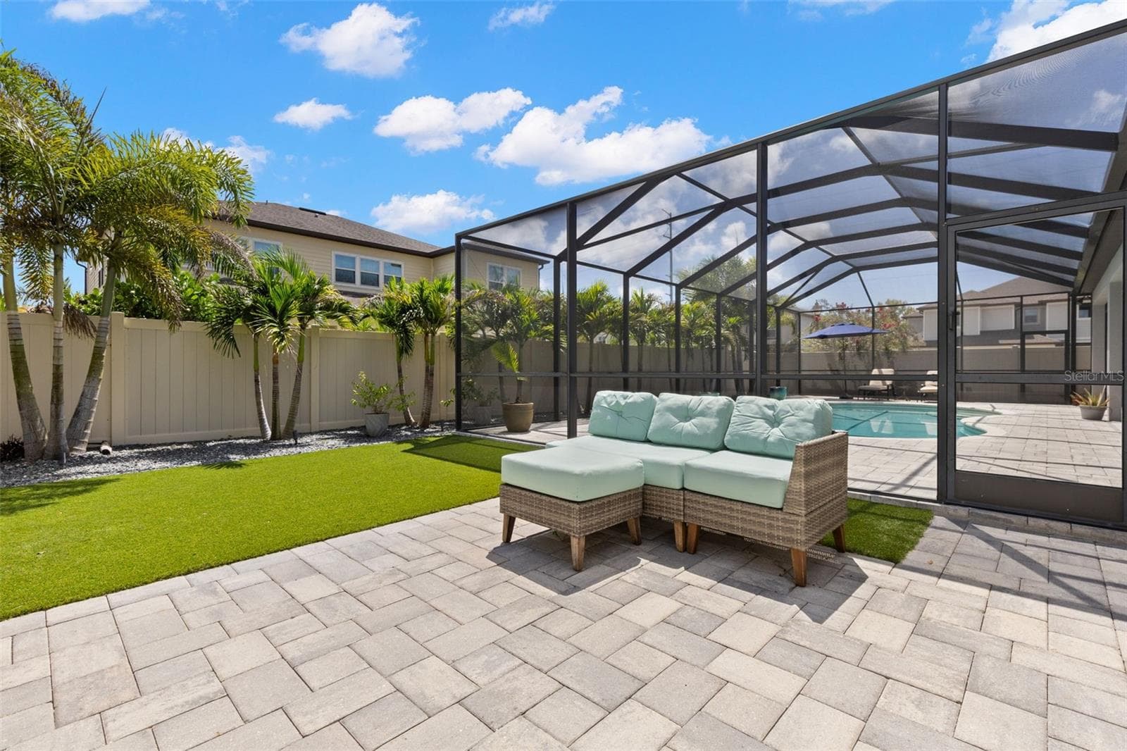 Beyond the screened pool enclosure, the backyard adds another inviting place to enjoy the outdoors, with low-maintenance artificial turf, an additional brick-paver patio, privacy fencing, and a row of palms that are beautifully illuminated after dark. - 1528 FOREST GLEN CT, PALM HARBOR
