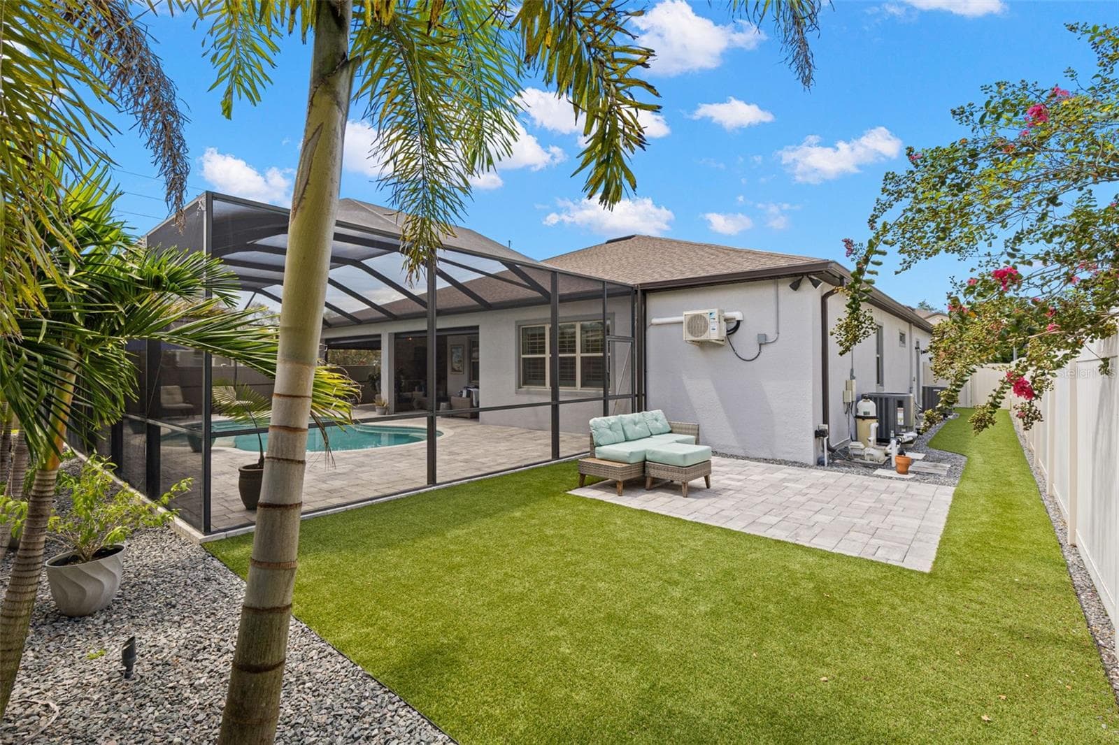 Beyond the screened pool enclosure, the backyard adds another inviting place to enjoy the outdoors, with low-maintenance artificial turf, an additional brick-paver patio, privacy fencing, and a row of palms that are beautifully illuminated after dark. - 1528 FOREST GLEN CT, PALM HARBOR