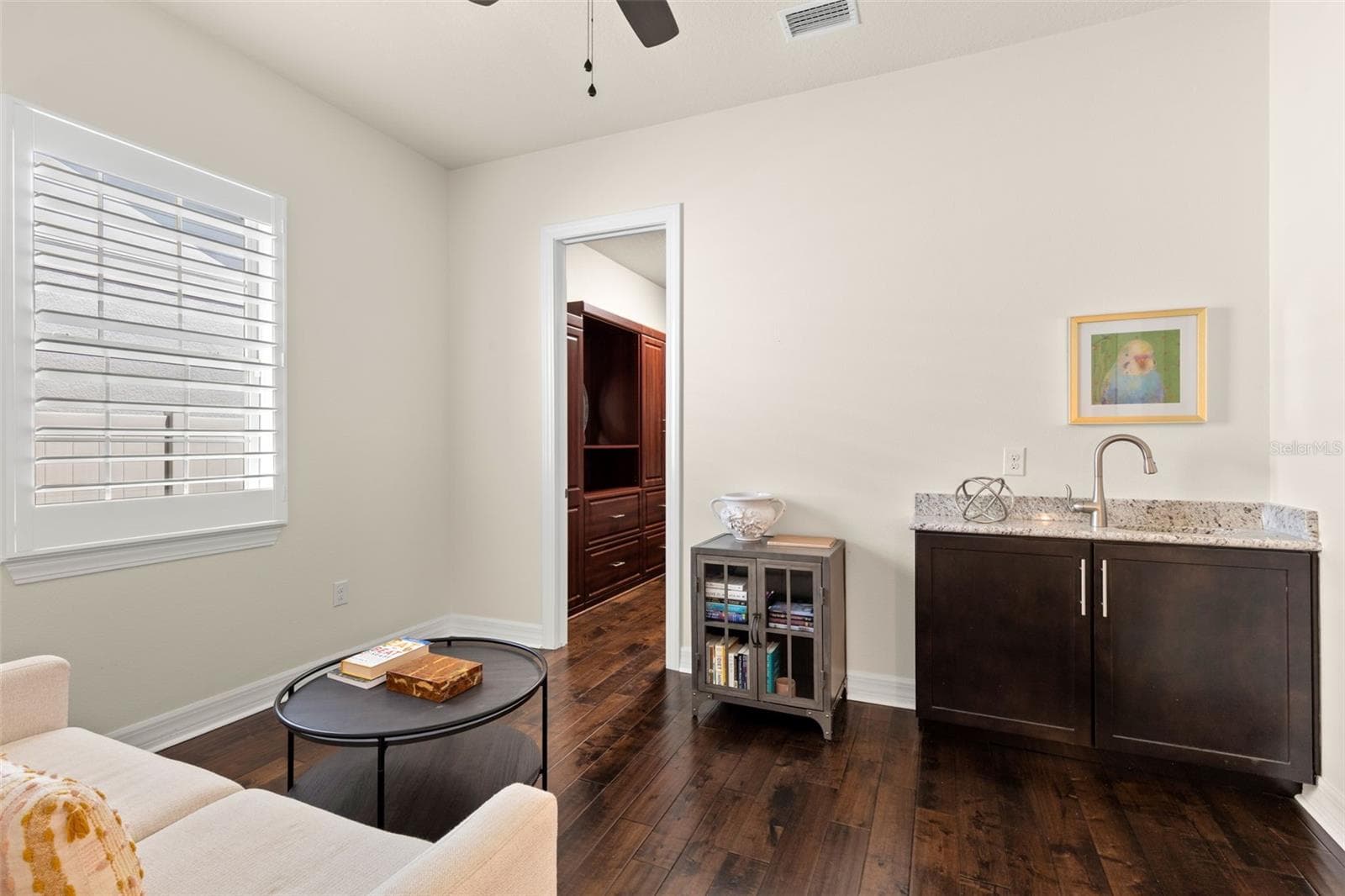 A closer look at the primary sitting area reveals its dedicated wet bar with granite counter, sink and cabinetry — perfect for morning coffee or an evening drink. Just beyond, one of the suite’s two walk-in closets adds impressive built-in storage. - 1528 FOREST GLEN CT, PALM HARBOR