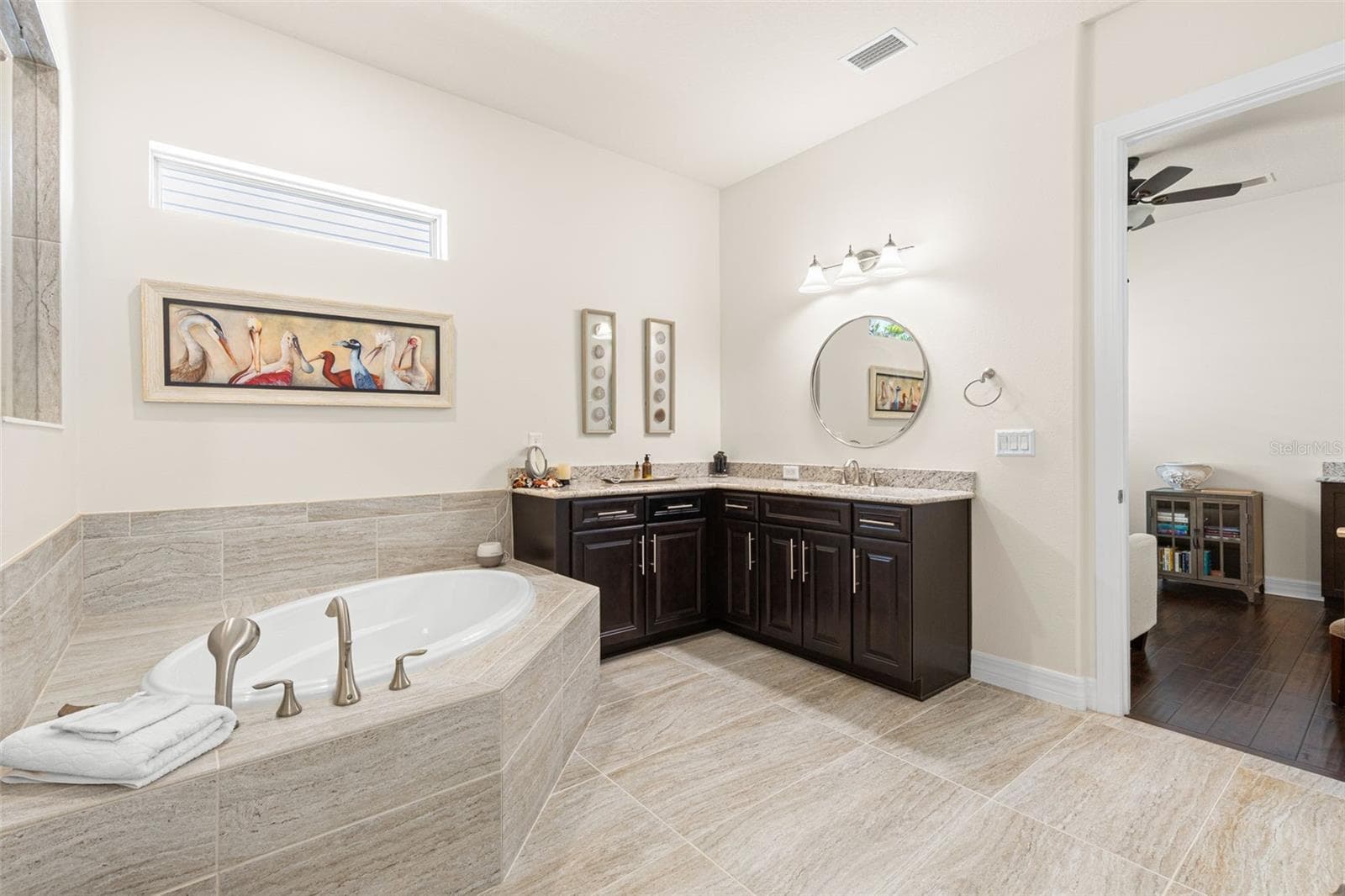 The primary bath continues the suite’s sense of space, with an inviting garden tub, expansive granite-topped vanity, rich cabinetry, and oversized tile carried across the floor and tub surround. A high transom window brings in natural light while maintaining privacy. - 1528 FOREST GLEN CT, PALM HARBOR