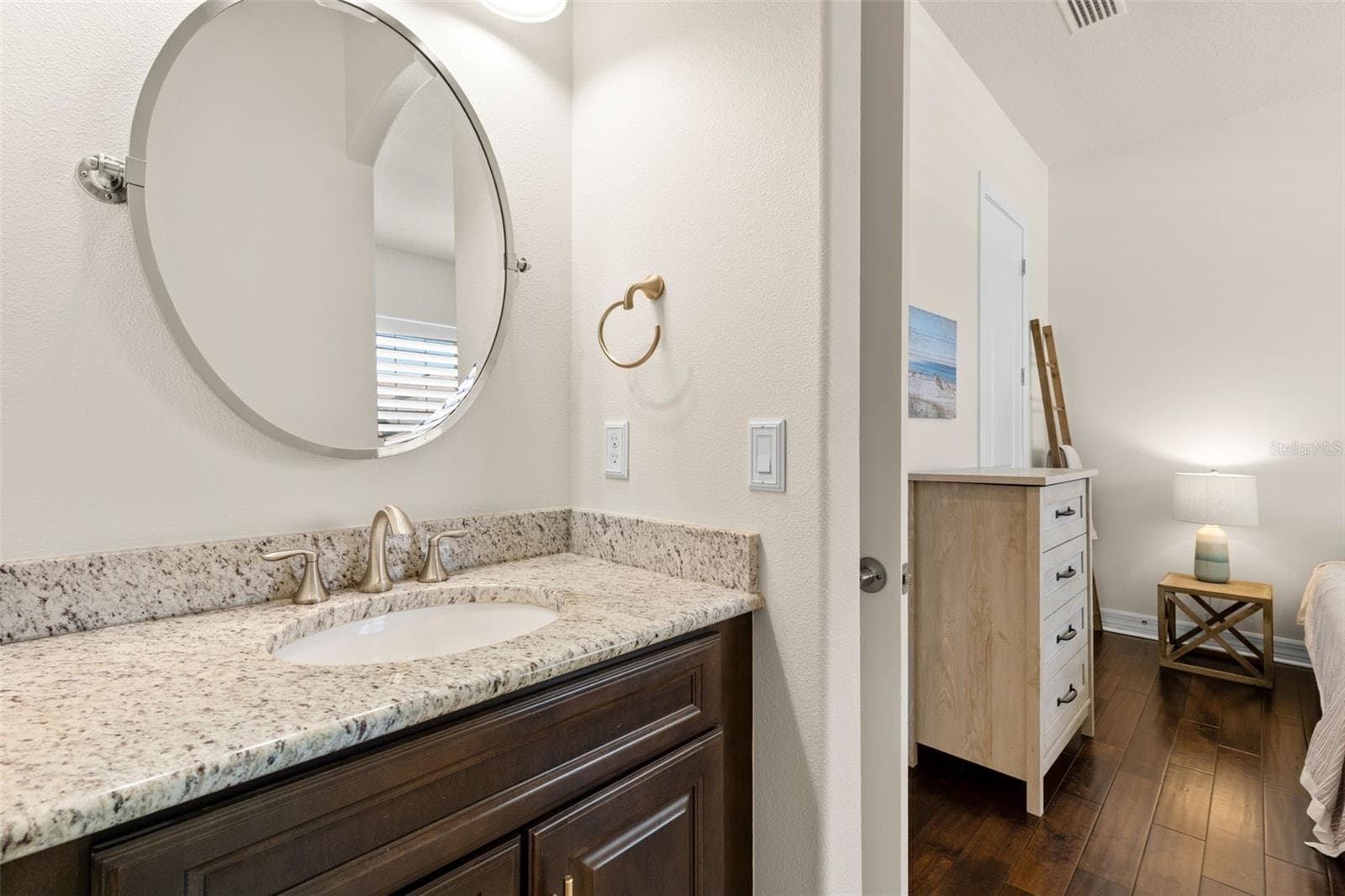 Bedroom 3 enjoys the same thoughtful Jack-and-Jill arrangement, with its own dedicated vanity, granite counter and rich cabinetry just outside the shared bath. Beyond, engineered hardwood flooring and neutral finishes continue into the bedroom, giving each space its own sense of separation. - 1528 FOREST GLEN CT, PALM HARBOR