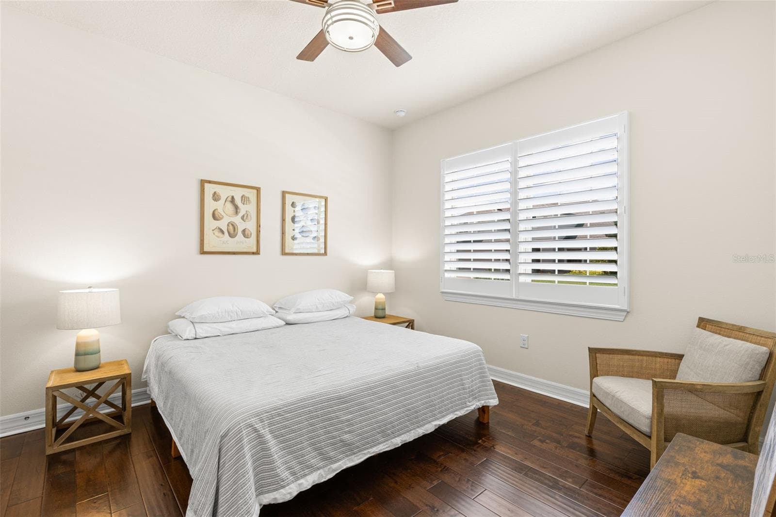 Bedroom 3 continues the home’s polished, neutral aesthetic with rich engineered hardwood flooring, plantation shutters, a ceiling fan and generous proportions that easily accommodate a full bedroom suite. Its dedicated vanity connects directly to the shared Jack-and-Jill bath just beyond. - 1528 FOREST GLEN CT, PALM HARBOR