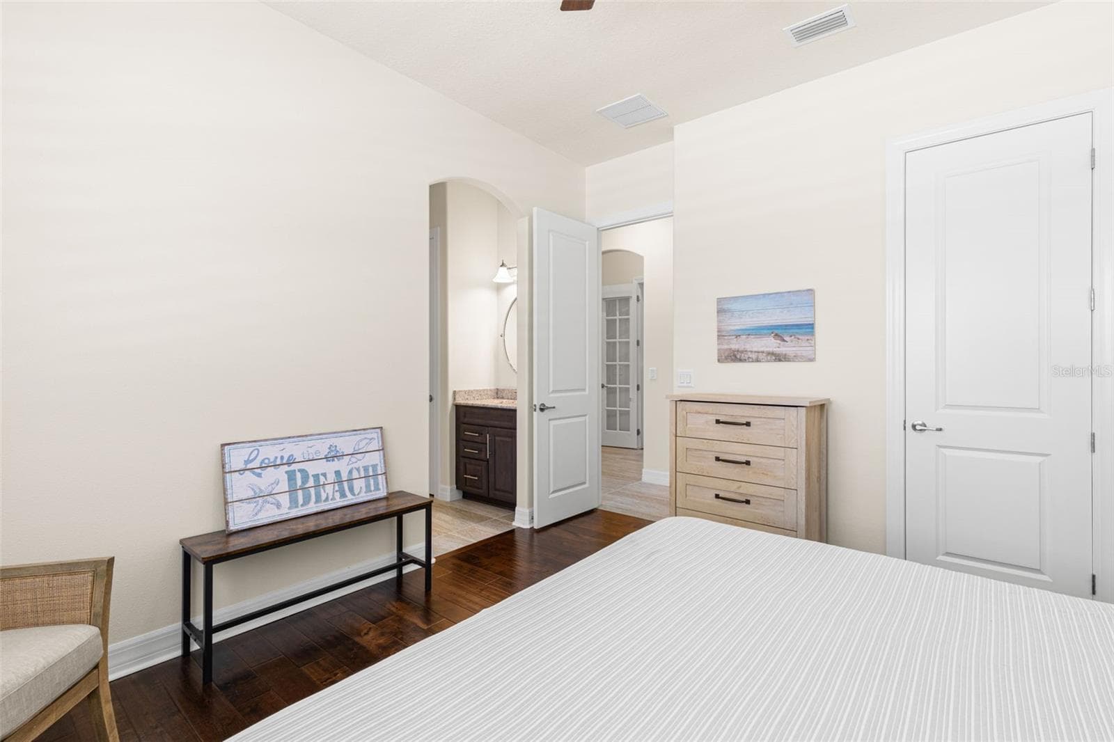 A second view of Bedroom 3 shows its easy connection to the dedicated vanity and shared Jack-and-Jill bath, while a separate closet, engineered hardwood flooring and generous wall space add to the room’s everyday function. - 1528 FOREST GLEN CT, PALM HARBOR