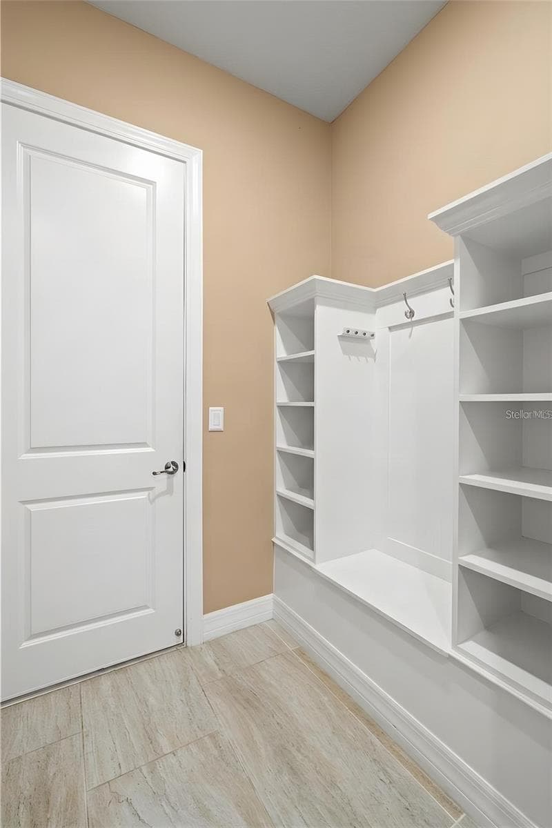 Just inside the garage, a dedicated mudroom creates a practical drop zone with a built-in bench, open shelving, hooks and storage cubbies, an ideal place to keep shoes, bags and everyday essentials organized before stepping into the main house. - 1528 FOREST GLEN CT, PALM HARBOR