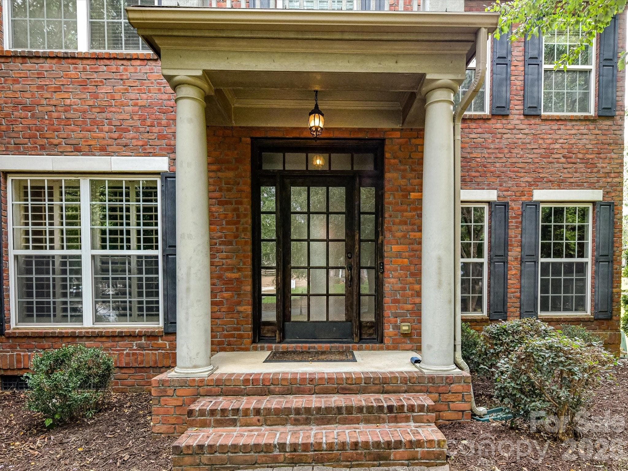 Classic brick exterior and a stately covered front entry create a welcoming first impression. - 11203 Warfield Avenue, Huntersville
