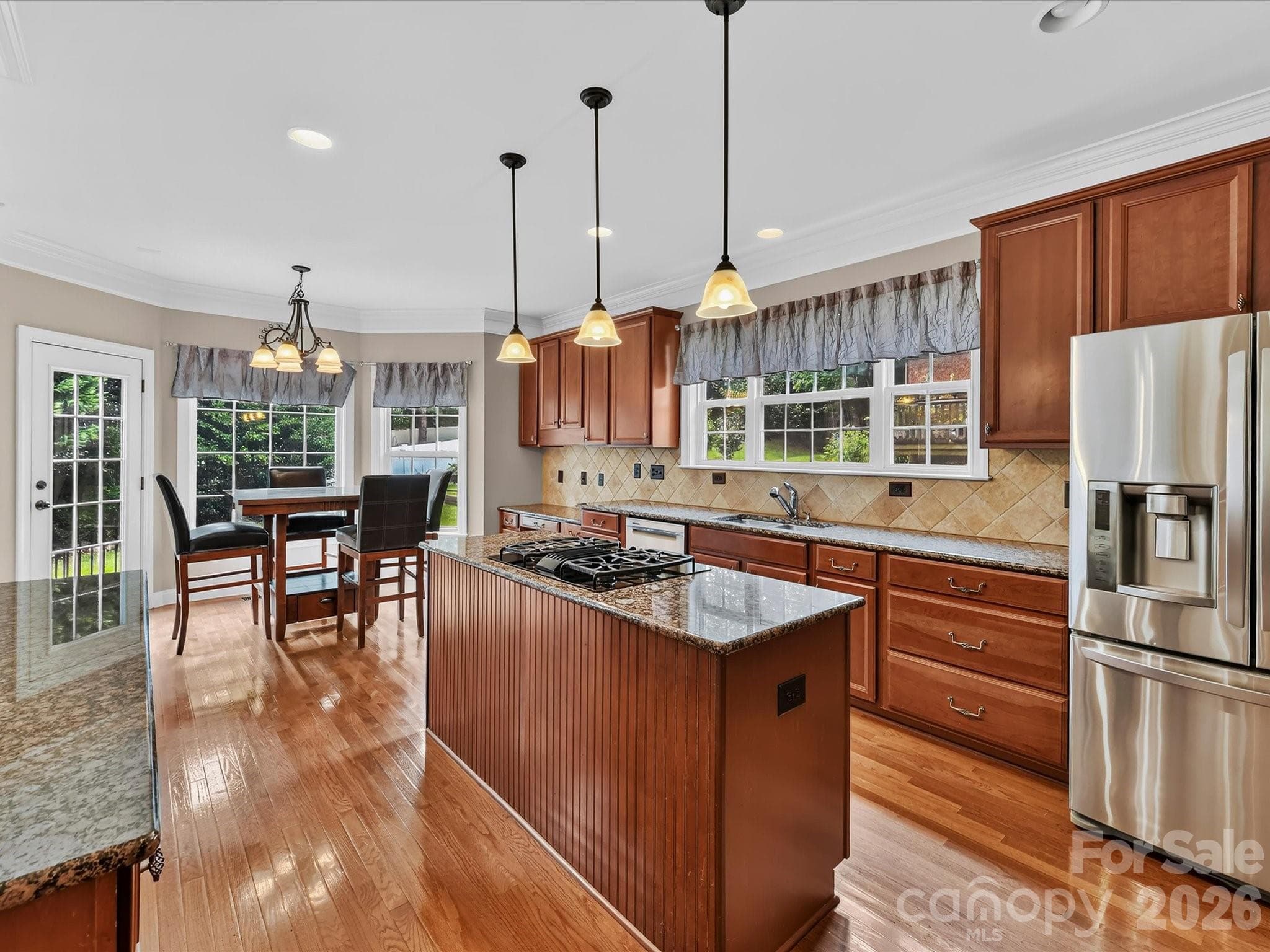 Generously sized kitchen showcasing granite countertops, stainless steel appliances, ample cabinetry, and a large center island with a built-in gas cooktop. - 11203 Warfield Avenue, Huntersville