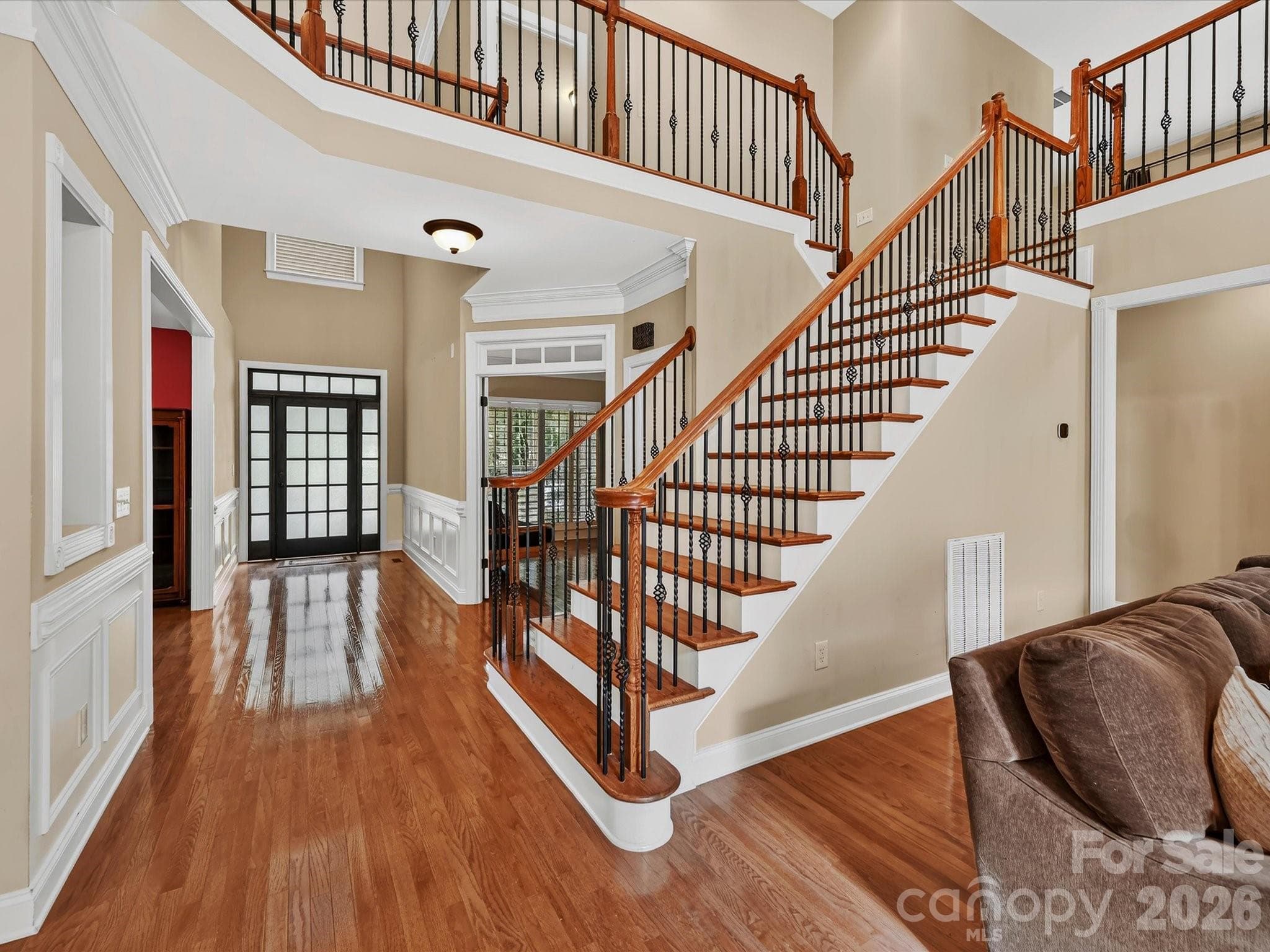 A grand two-story foyer showcases gleaming hardwood floors, elegant millwork, and a striking staircase with rich wood accents and wrought-iron balusters. - 11203 Warfield Avenue, Huntersville