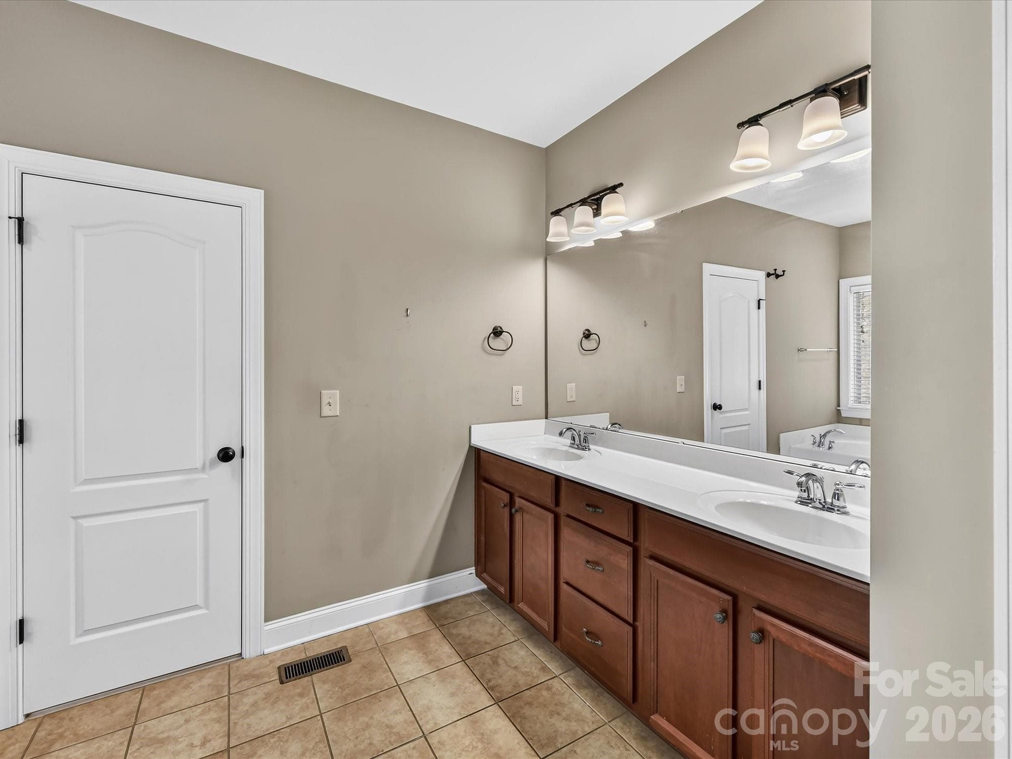 Spacious primary bath features a long dual-sink vanity, generous counter space, and convenient access to the walk-in closet - 11203 Warfield Avenue, Huntersville