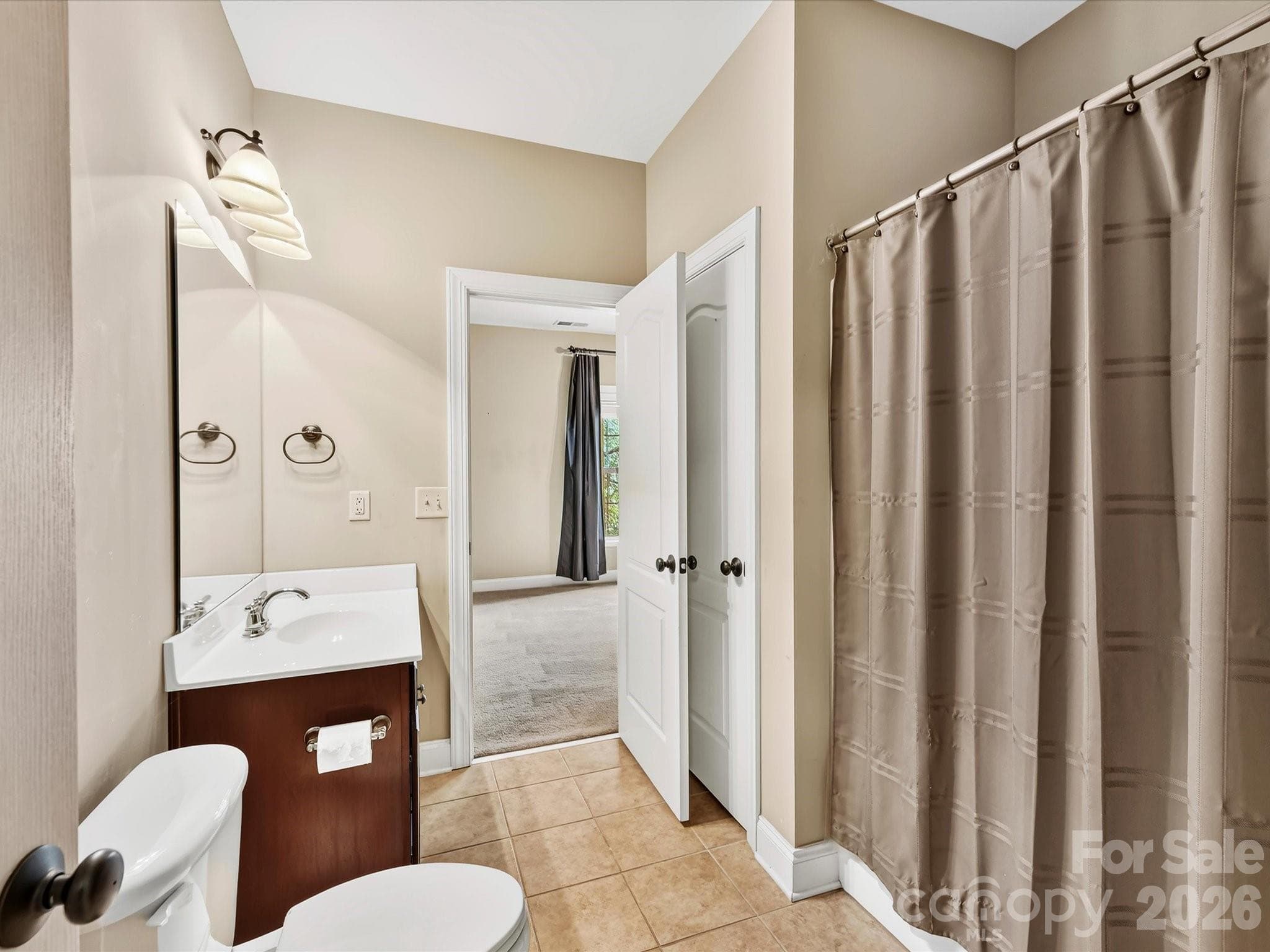 Bright secondary bathroom featuring a spacious vanity, tiled flooring, and a tub/shower combination with convenient access to the adjoining bedroom. - 11203 Warfield Avenue, Huntersville