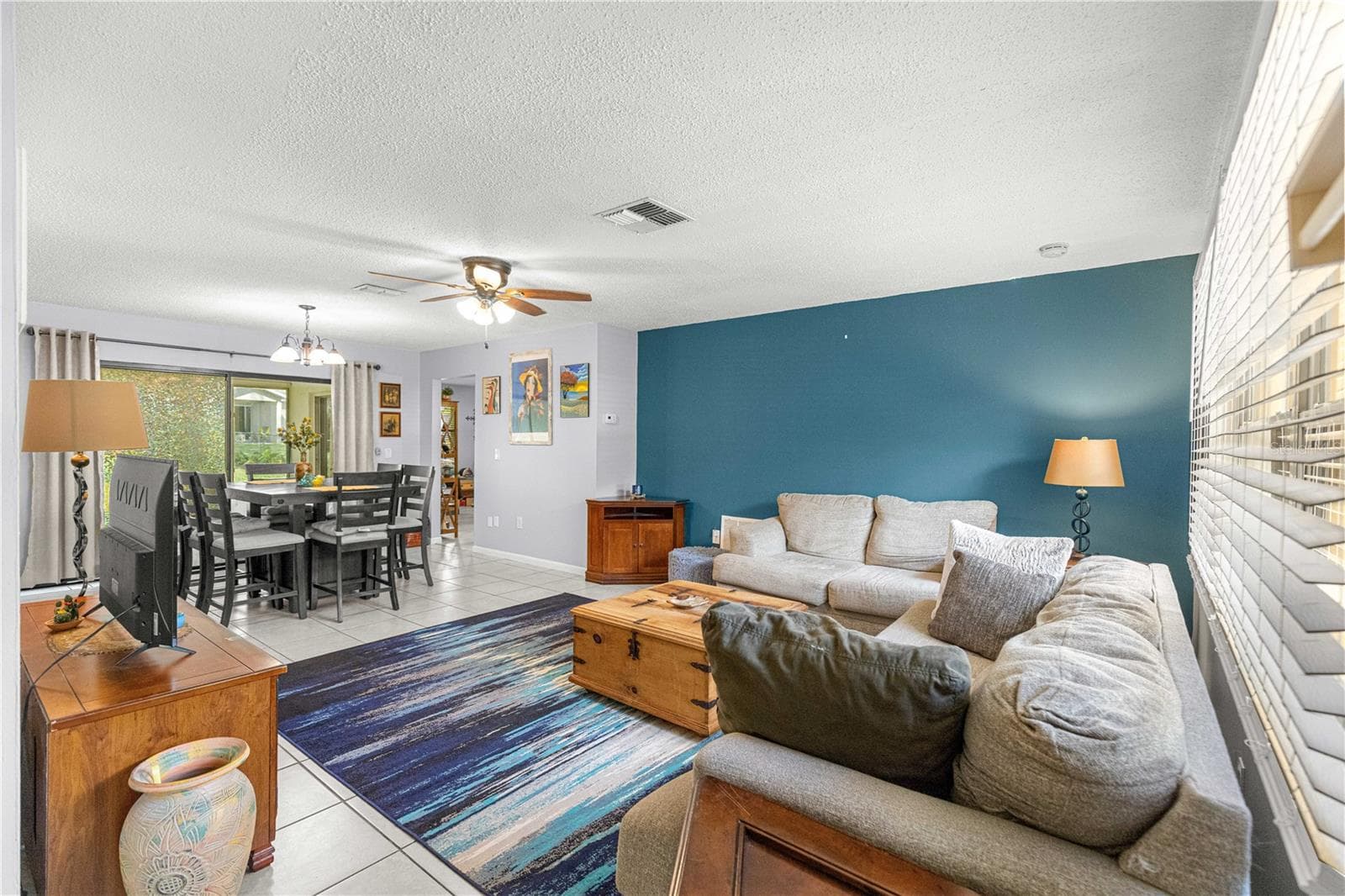 Living room with tile flooring, a ceiling fan and a wide window overlooking the front yard. - 2170 W DORAL CT, CITRUS SPRINGS