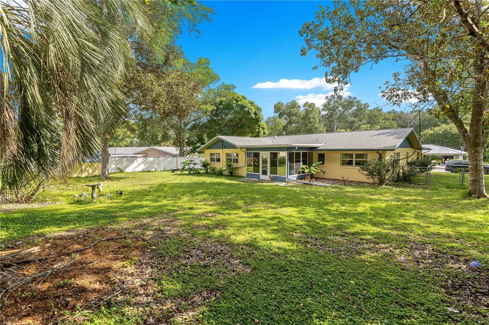 Rear exterior showing the enclosed porch and established yard. - 2170 W DORAL CT, CITRUS SPRINGS