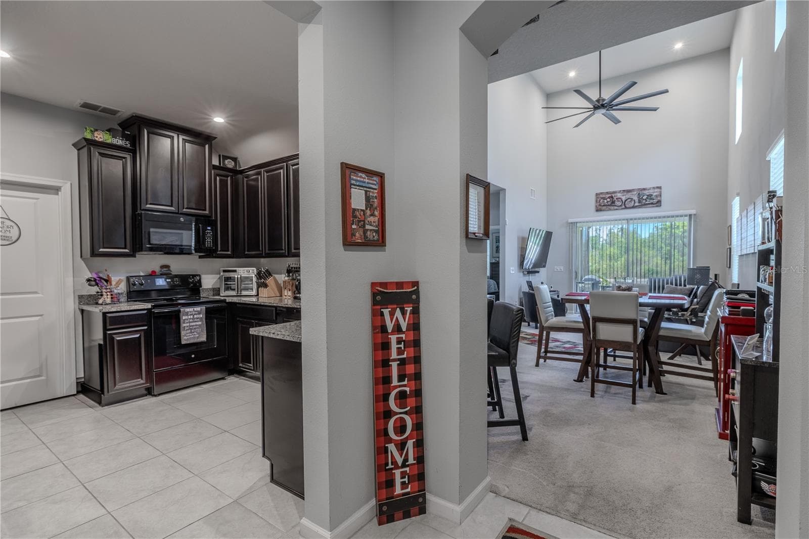 Vaulted ceilings add volume to the main living and dining area, where high-set windows and expansive glass bring in natural light and frame the green-space backdrop beyond. - 3029 JACOB CROSSING LN, HOLIDAY