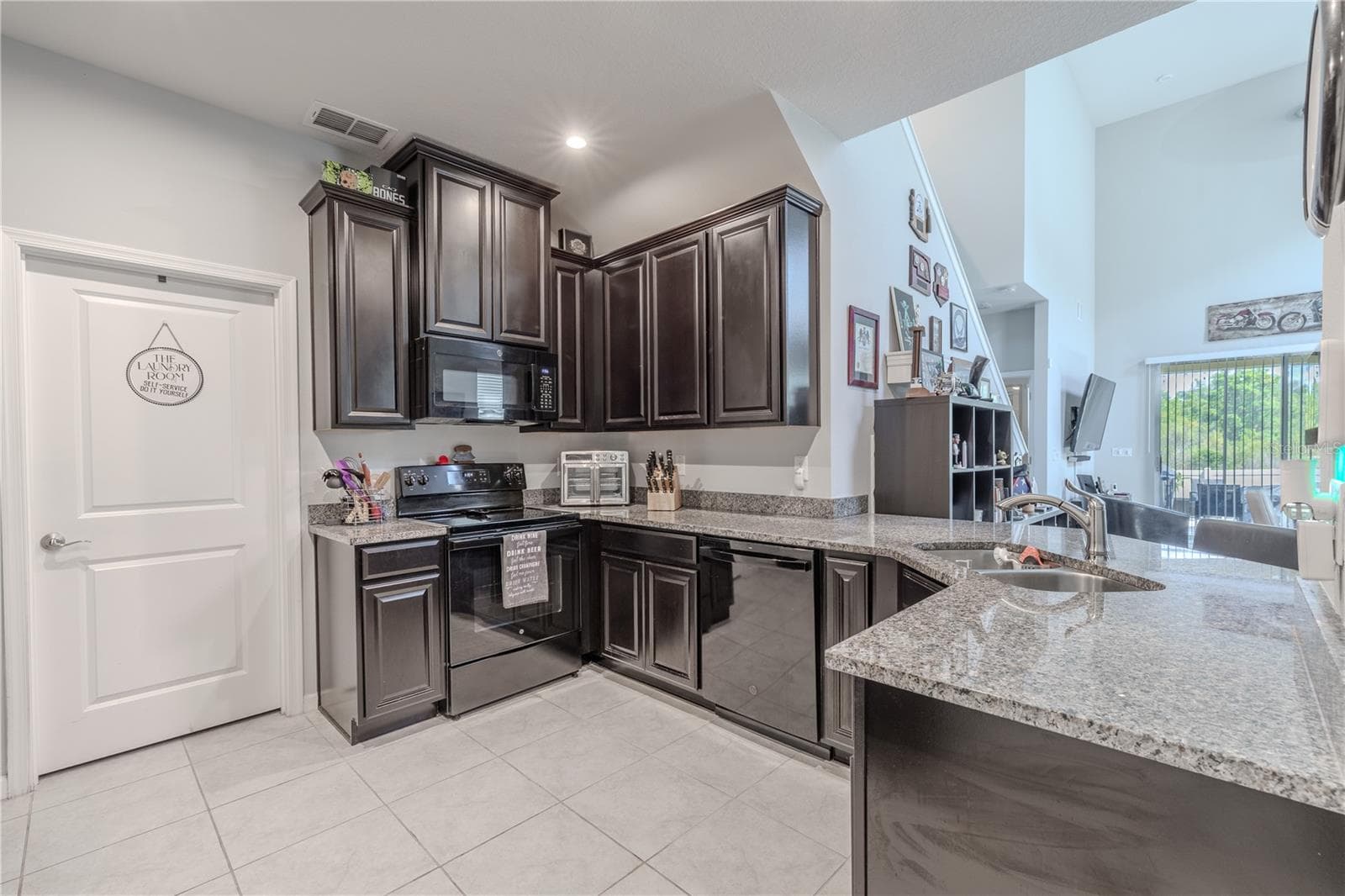 Dark raised-panel cabinetry, granite counters, ceramic tile flooring and a spacious peninsula give the kitchen plenty of workspace while keeping it connected to the adjoining living area. - 3029 JACOB CROSSING LN, HOLIDAY