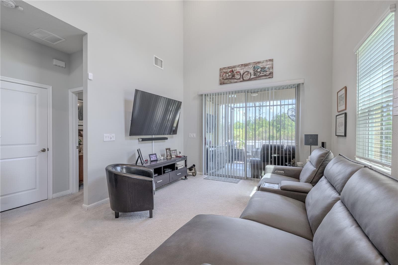 A soft neutral palette, high ceiling and generous natural light give the living room a bright, easygoing feel, with sliding glass doors opening directly to the screened lanai. - 3029 JACOB CROSSING LN, HOLIDAY