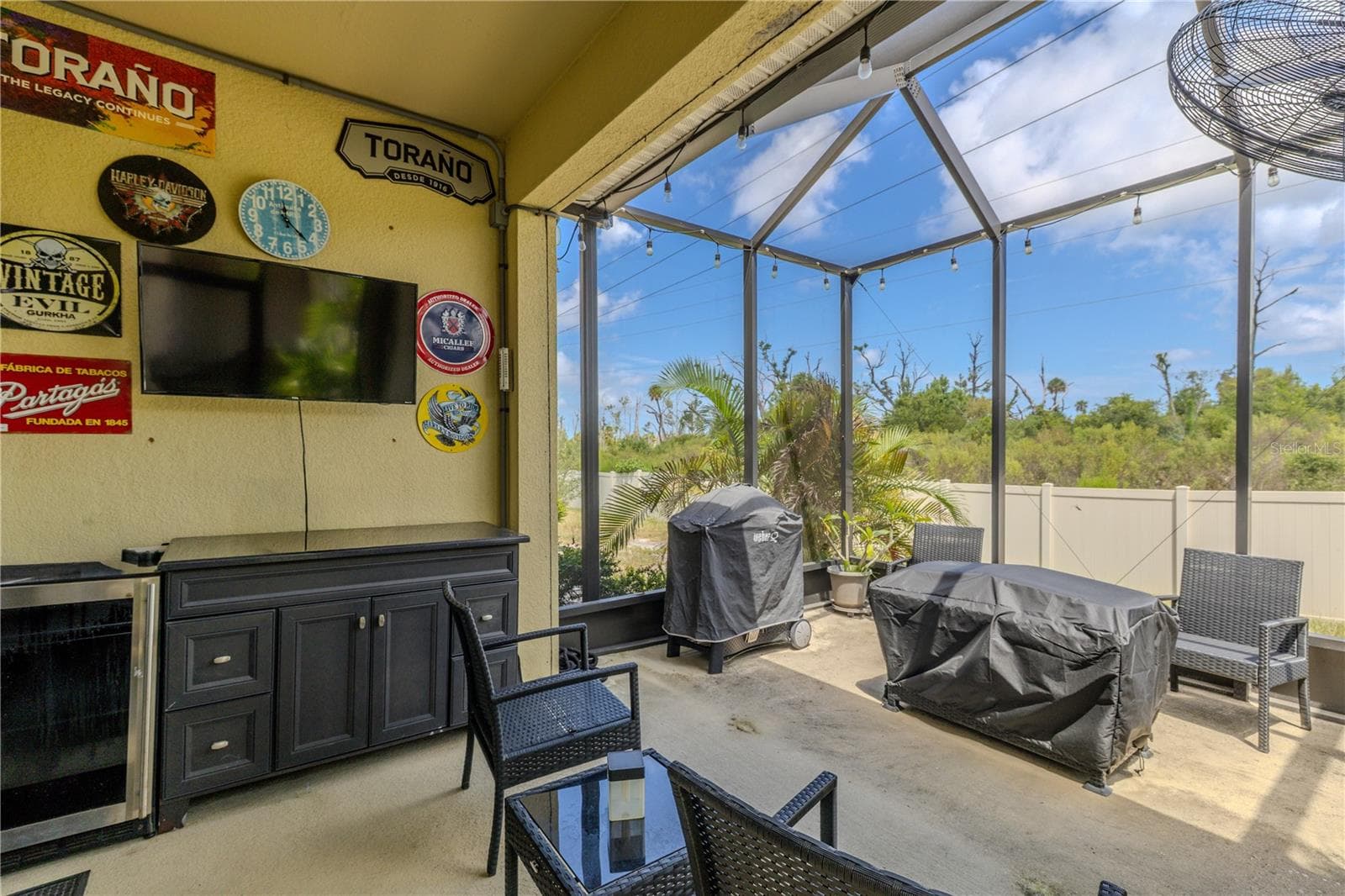Designed for easy outdoor entertaining, the covered lanai offers space for seating, storage and a wall-mounted TV setup, then flows into the extended screened patio with grilling space and green views beyond. Wall mount conveys; TV does not. - 3029 JACOB CROSSING LN, HOLIDAY