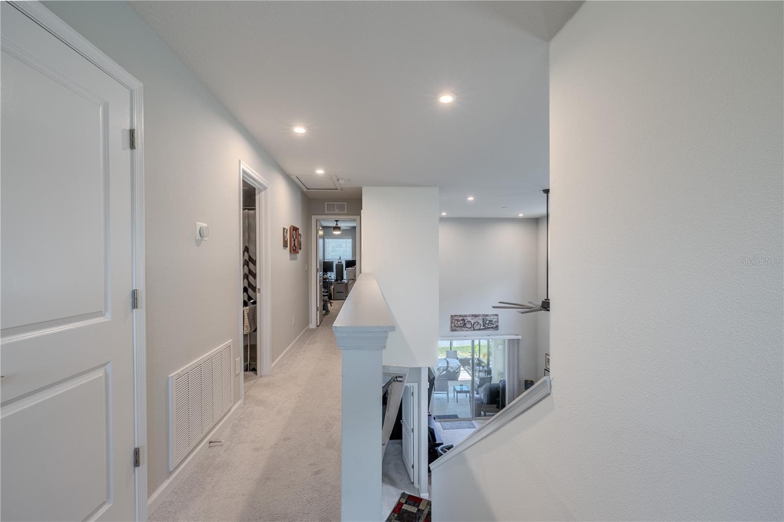 The upstairs hall overlooks the main living area below, with recessed lighting, neutral carpet and an open railing that keeps the second floor feeling connected to the home’s dramatic central space. - 3029 JACOB CROSSING LN, HOLIDAY
