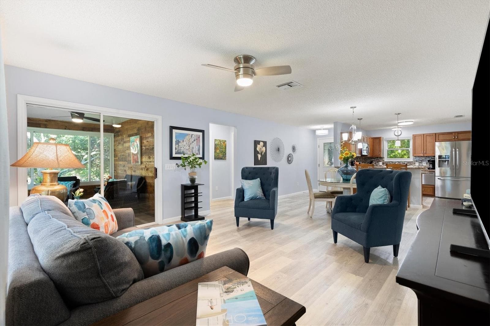OPEN CONCEPT DINING, LIVING ROOM AND KITCHEN, SLIDING DOOR LEAD TO A TINTED GLASS ENCLOSED LANAI WITH A MINI SPLIT FOR ALL YEAR COMFORT. - 1426 JUAREZ PL, THE VILLAGES