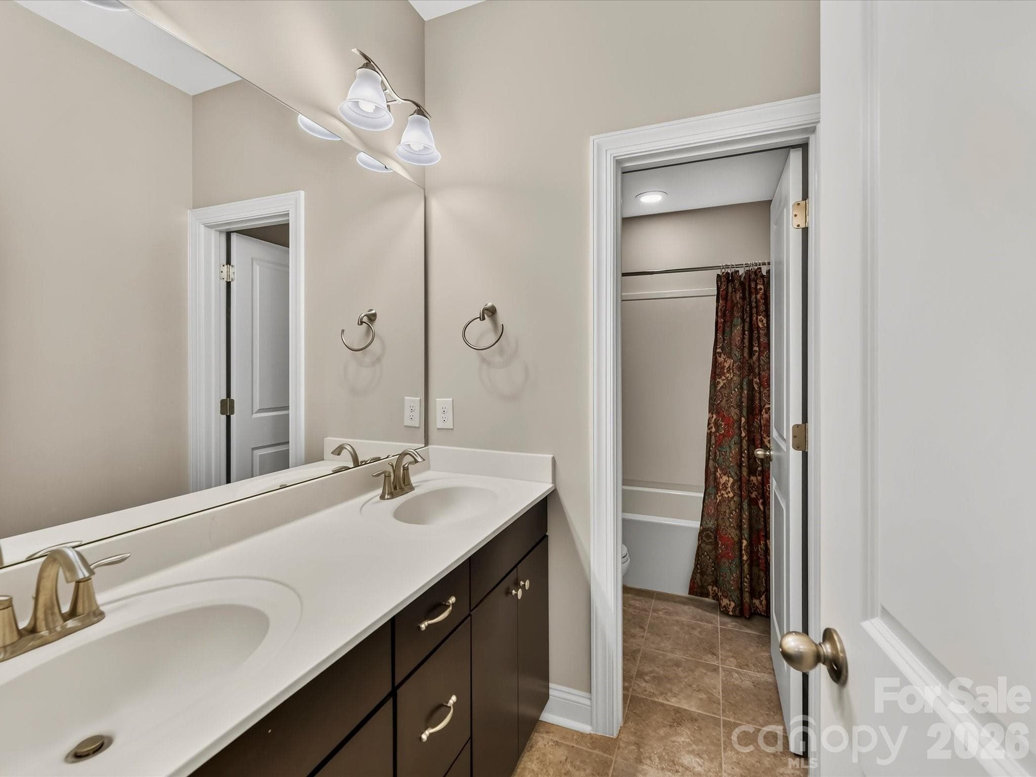Hall bath with dual vanities, tiled floor, and tub/shower combo. - 12323 Cherrybark Lane, Charlotte